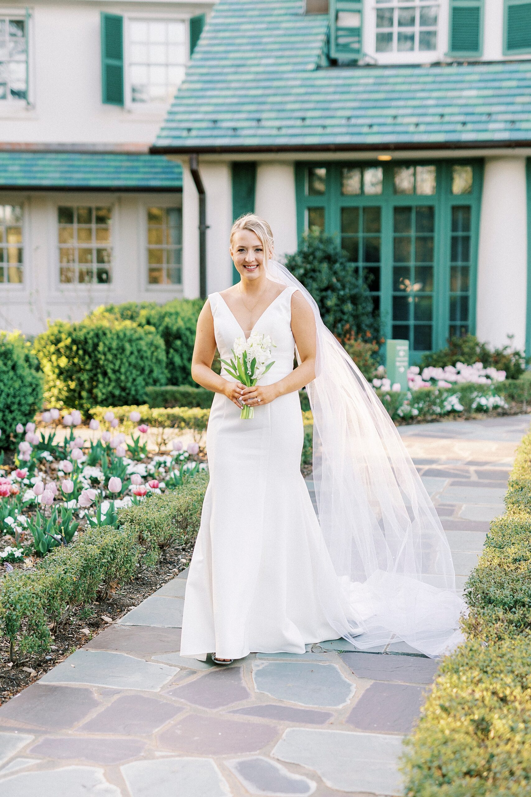 bride walks in front of green and white house at Reynolda Gardens