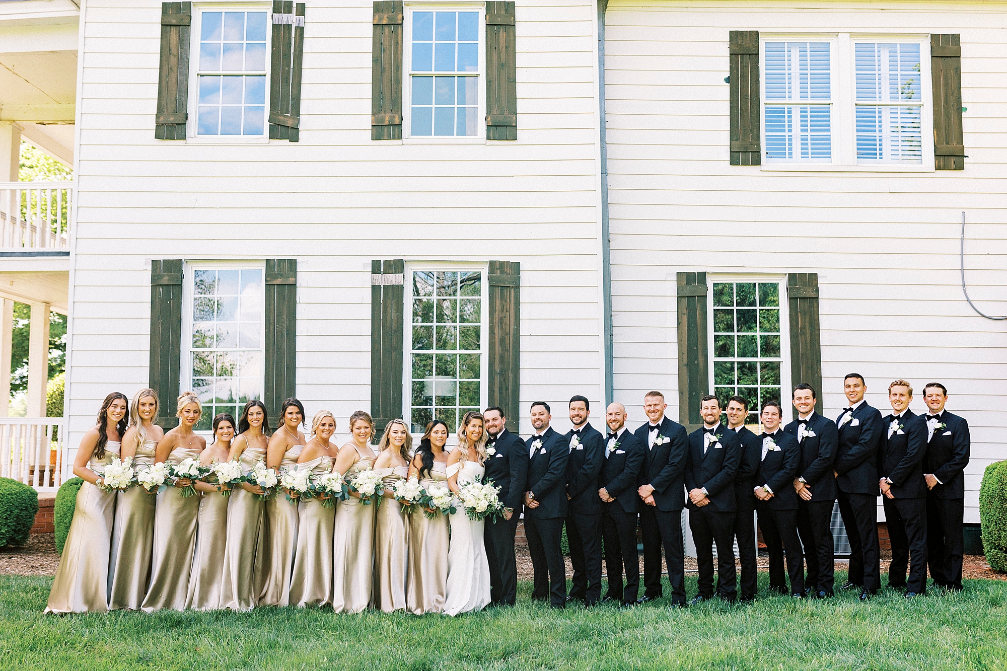 bride and groom stand with wedding party outside the Venues at Langtree