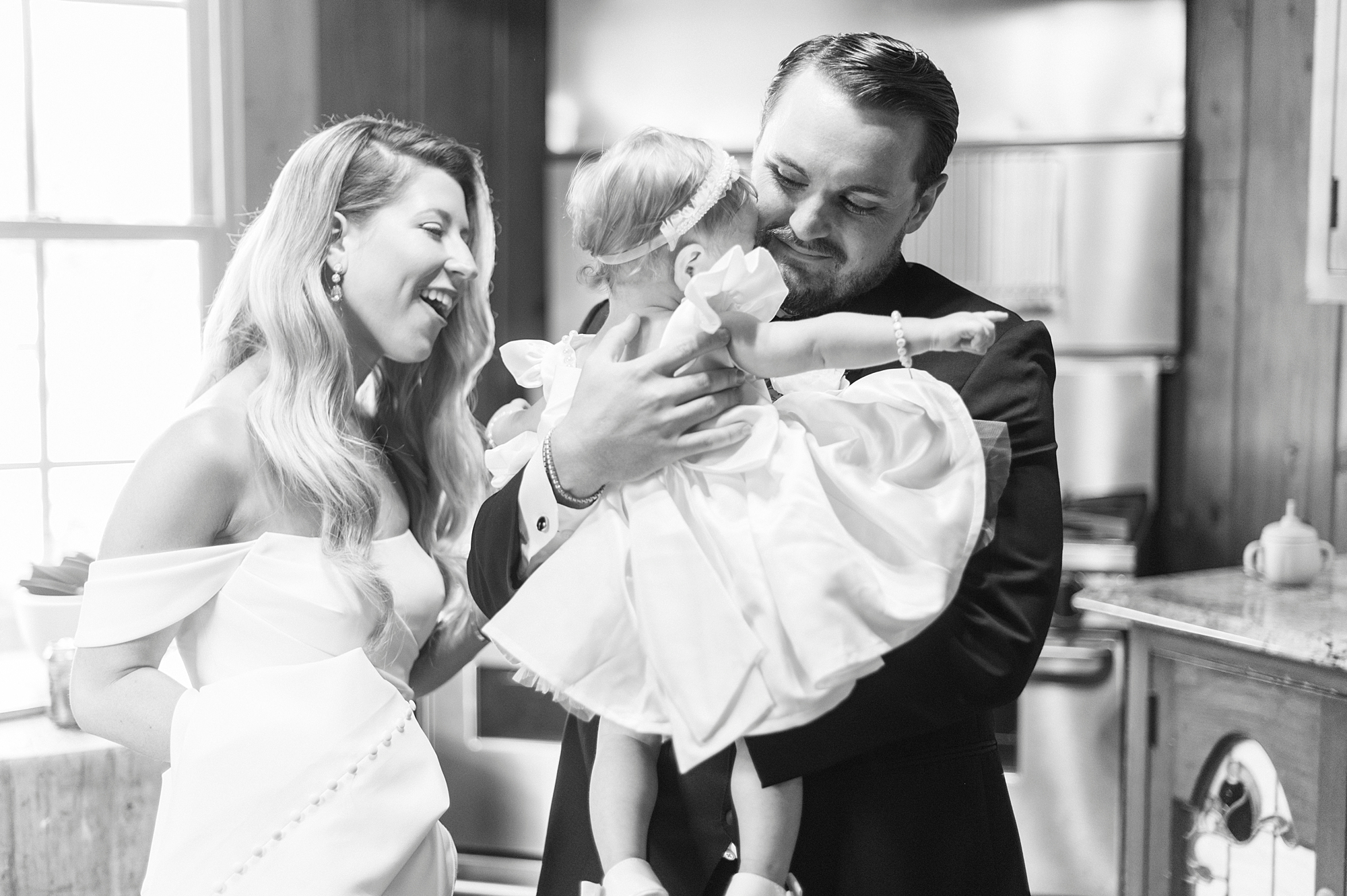bride and groom hug young daughter on day of wedding