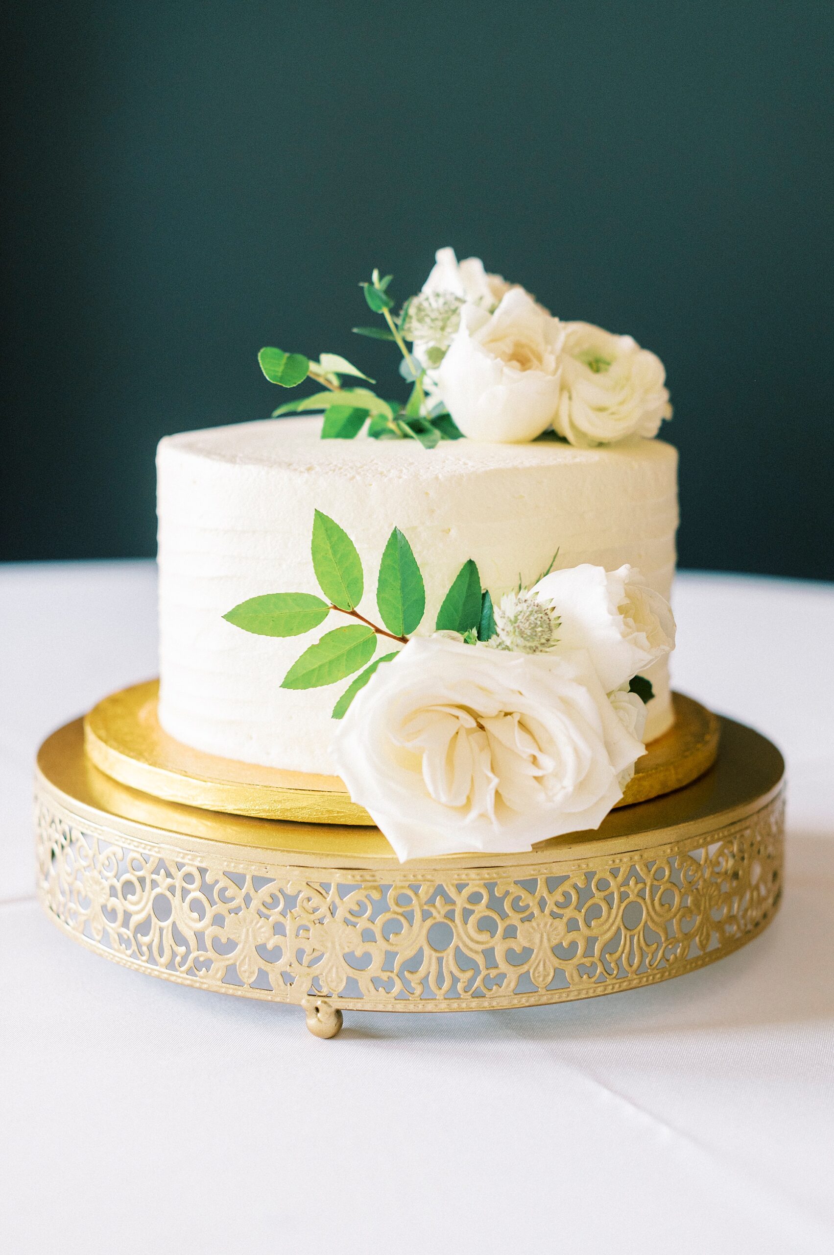 one tiered wedding cake on gold stand with ivory florals