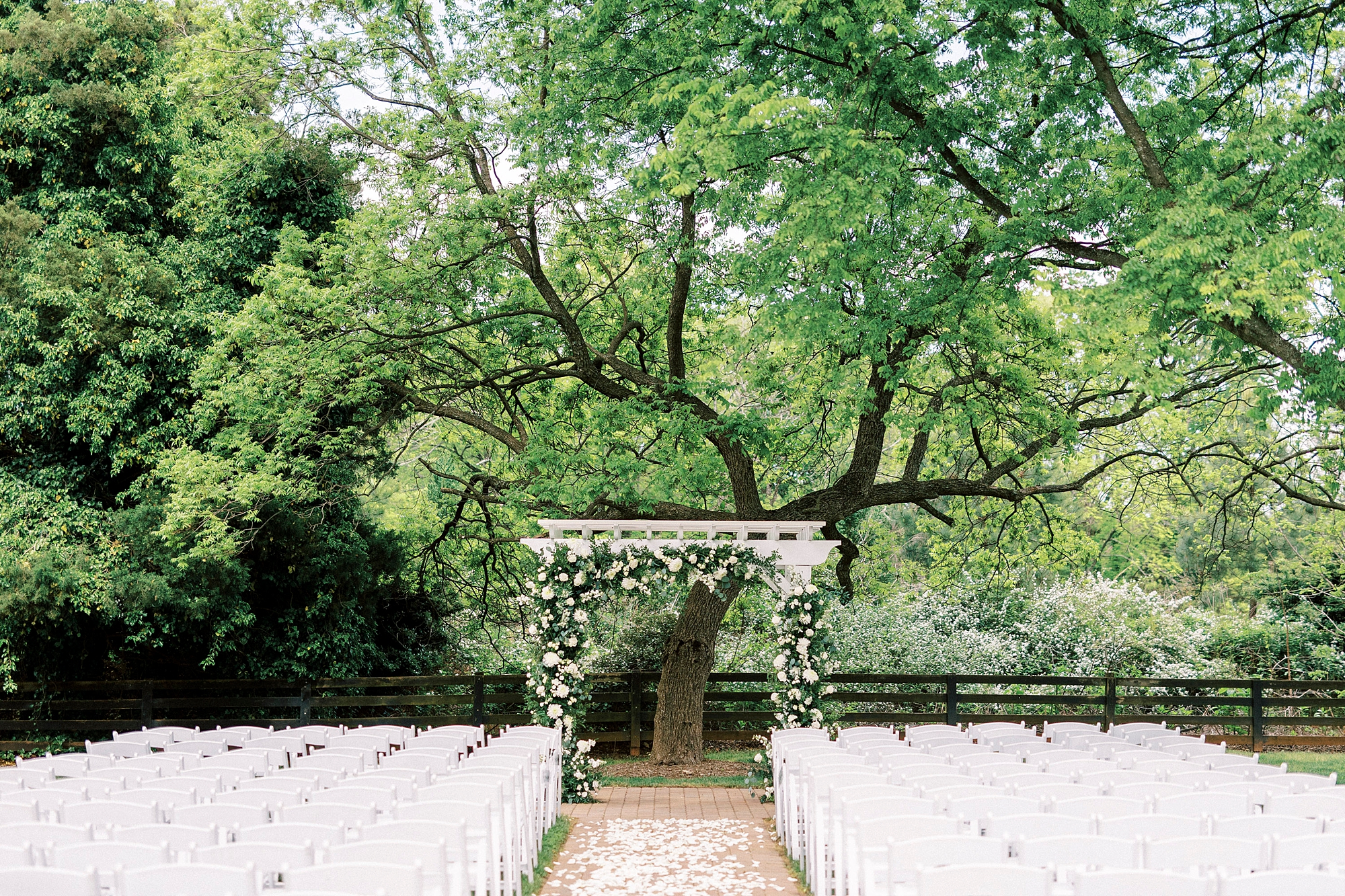 ceremony site with white chairs and arbor with white flowers at the Venues at Langtree