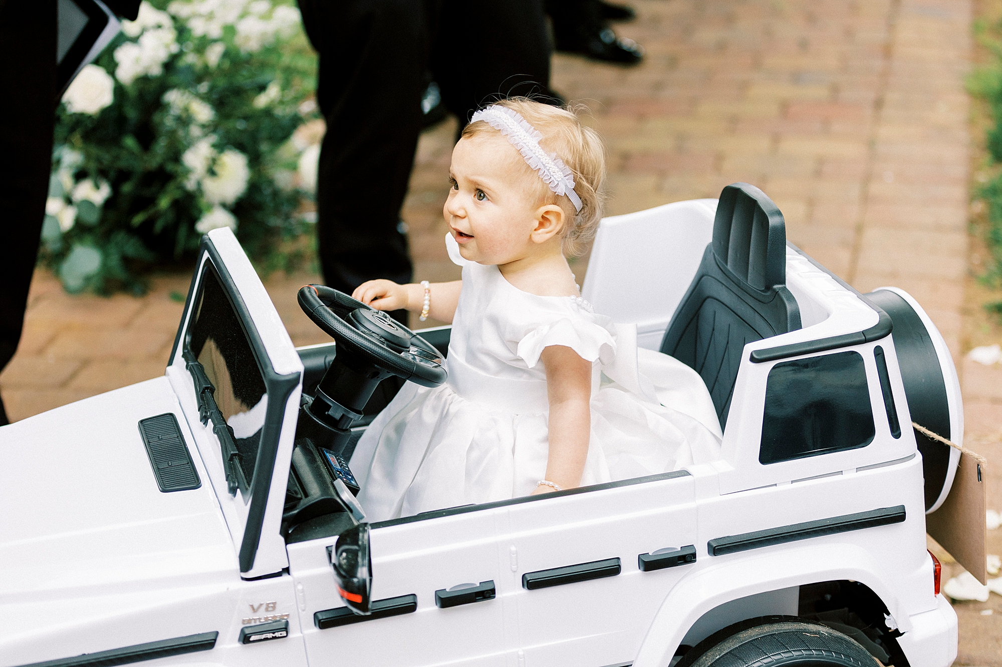 flower girl in white dress drives white jeep down aisle