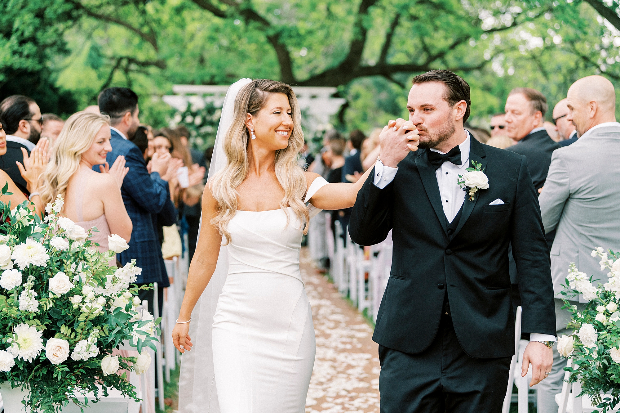 groom kisses bride's hand walking up aisle after ceremony at the Venues at Langtree