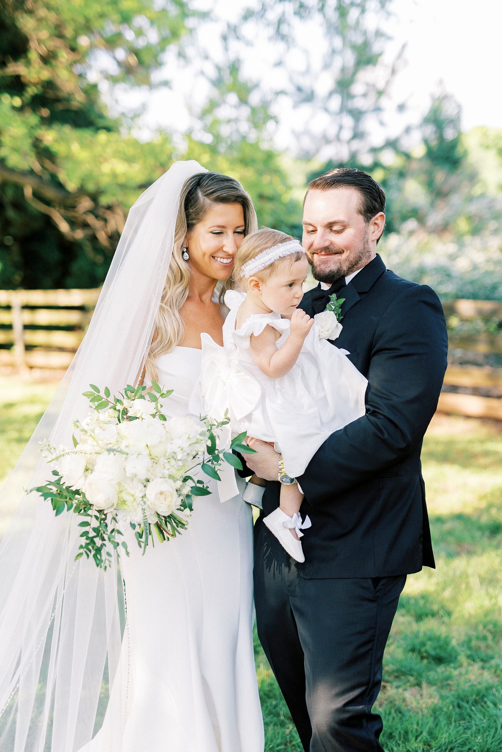 bride and groom pose with daughter in white dress