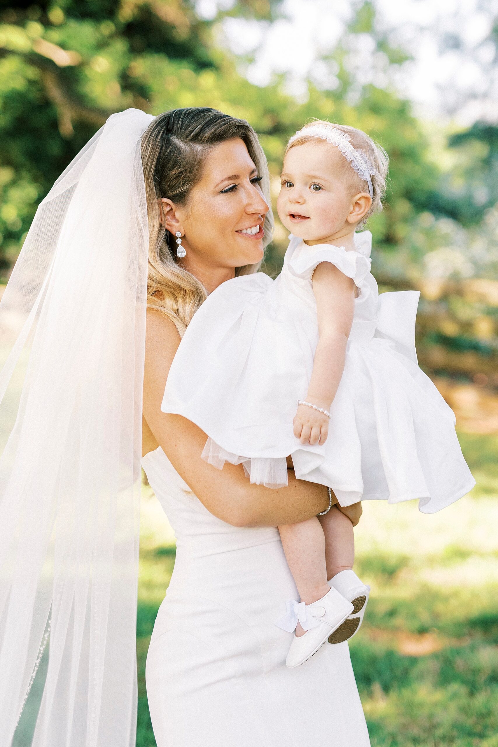 bride smiles holding daughter on hip during wedding day
