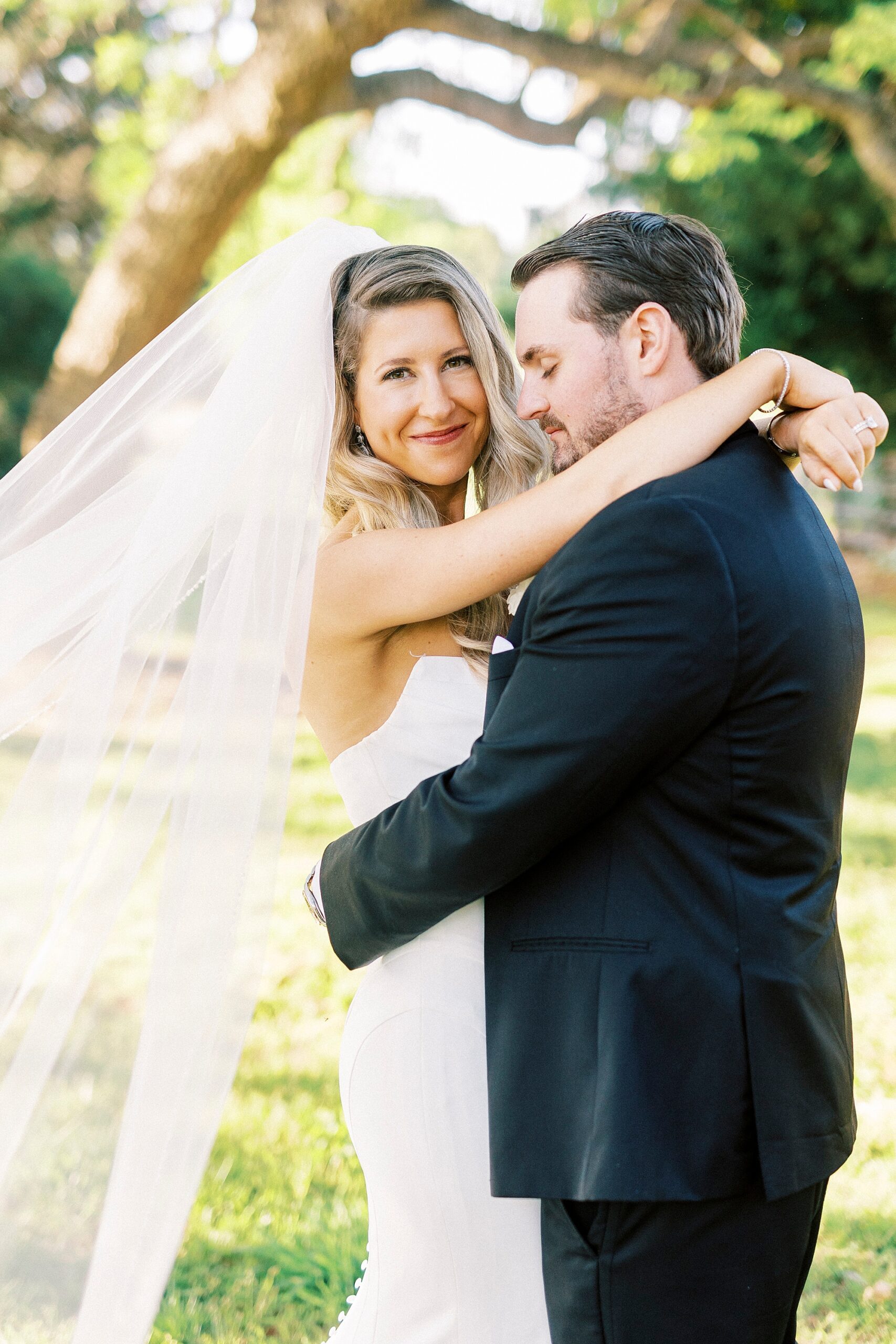groom smiles at bride hugging around her hips at the Venues at Langtree