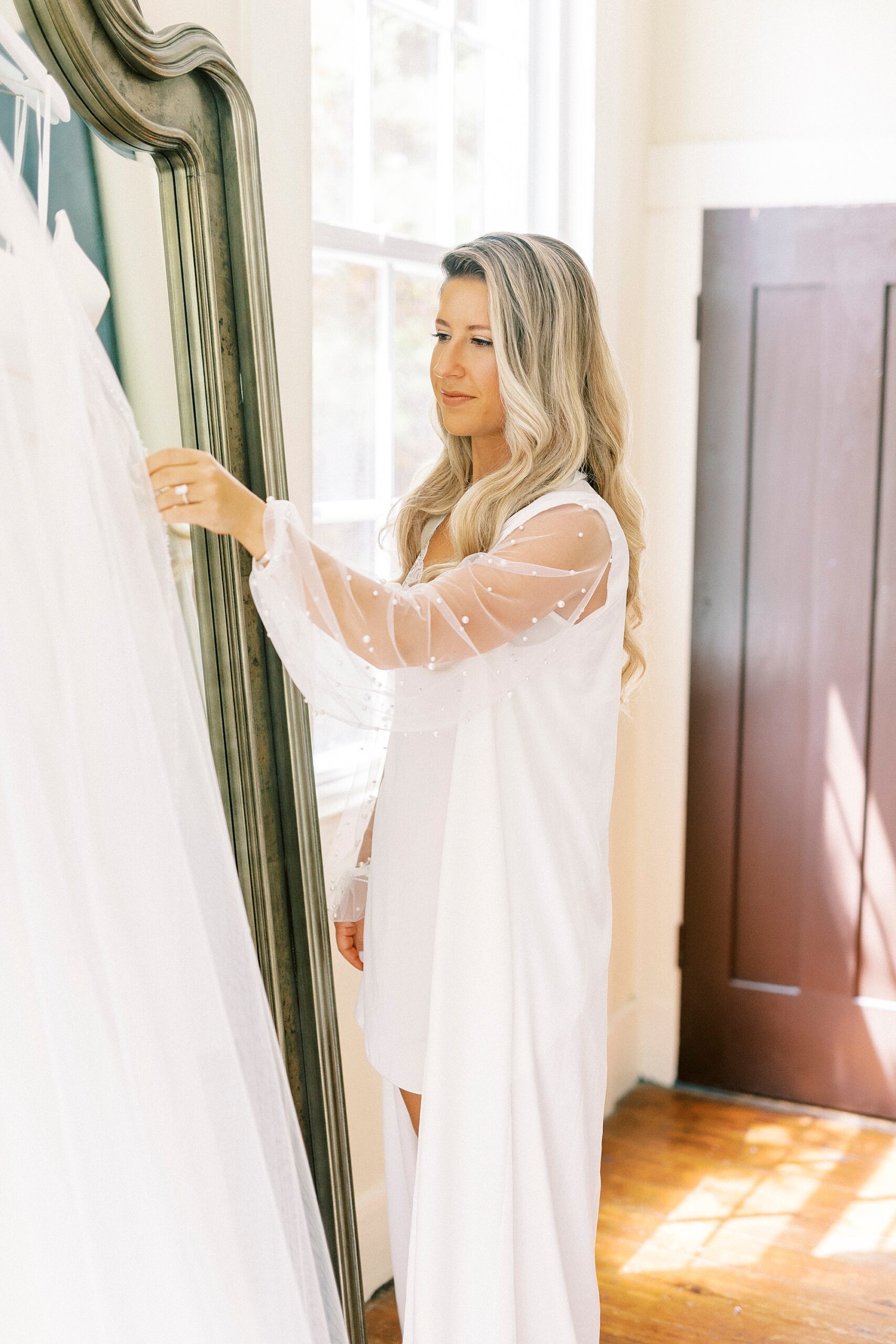 woman looks at wedding dress hanging on mirror at the Venues at Langtree