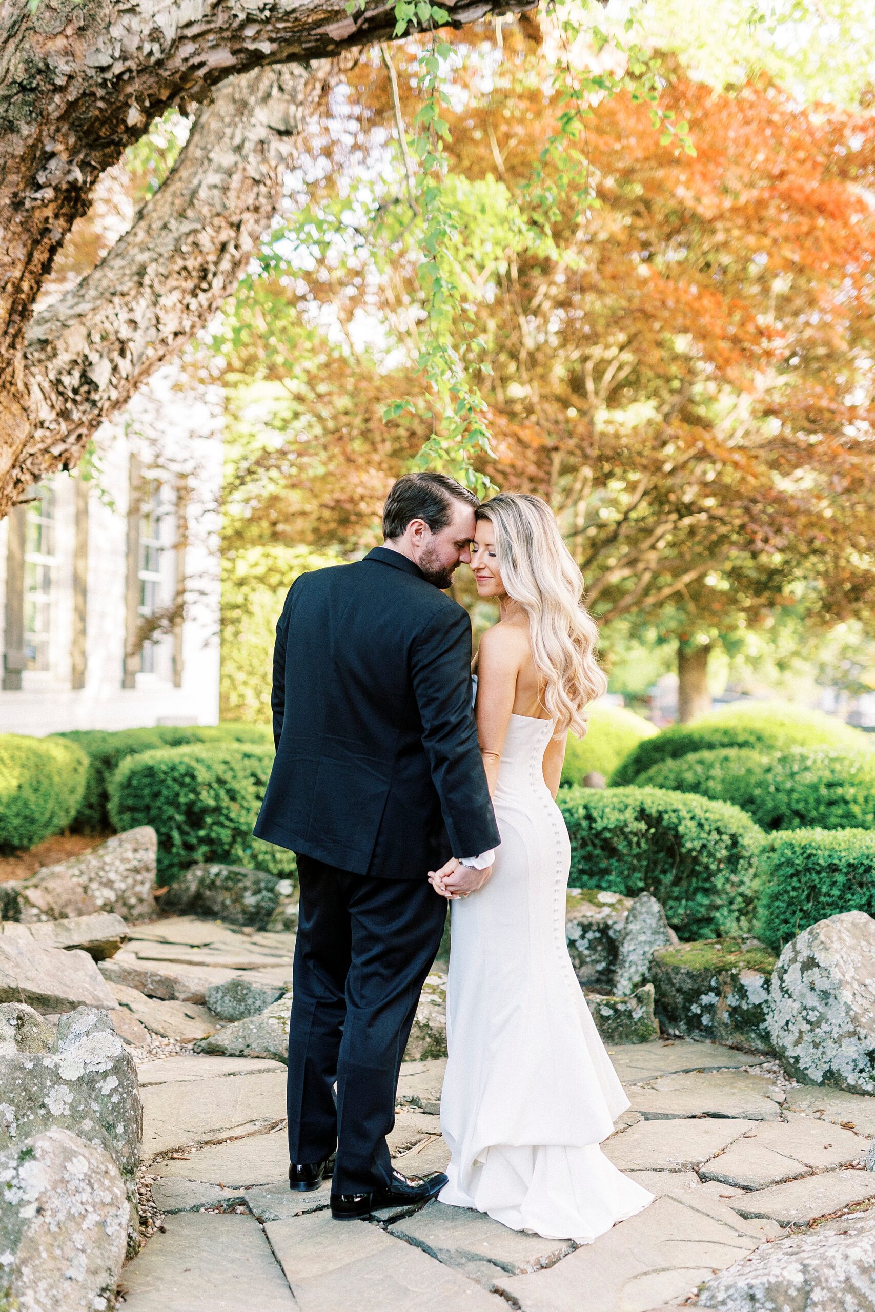 groom leans to nuzzle bride's cheek on brick path at the Venues at Langtree