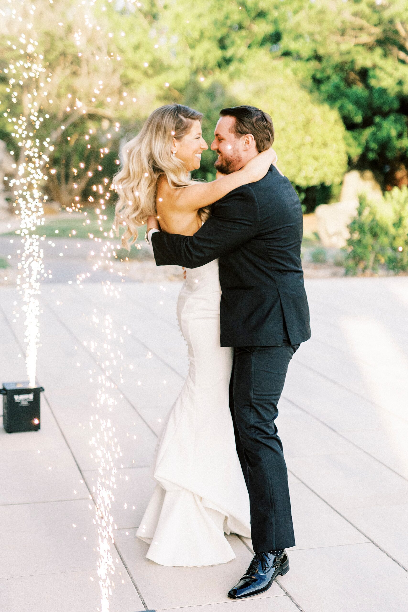 groom hugs bride leaning to kiss her near sparklers at the Venues at Langtree