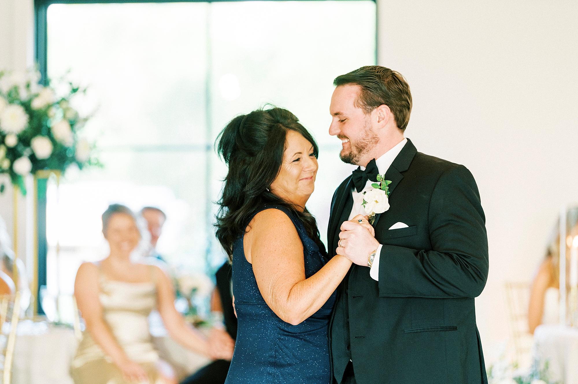 groom smiles at mother dancing during NC wedding reception
