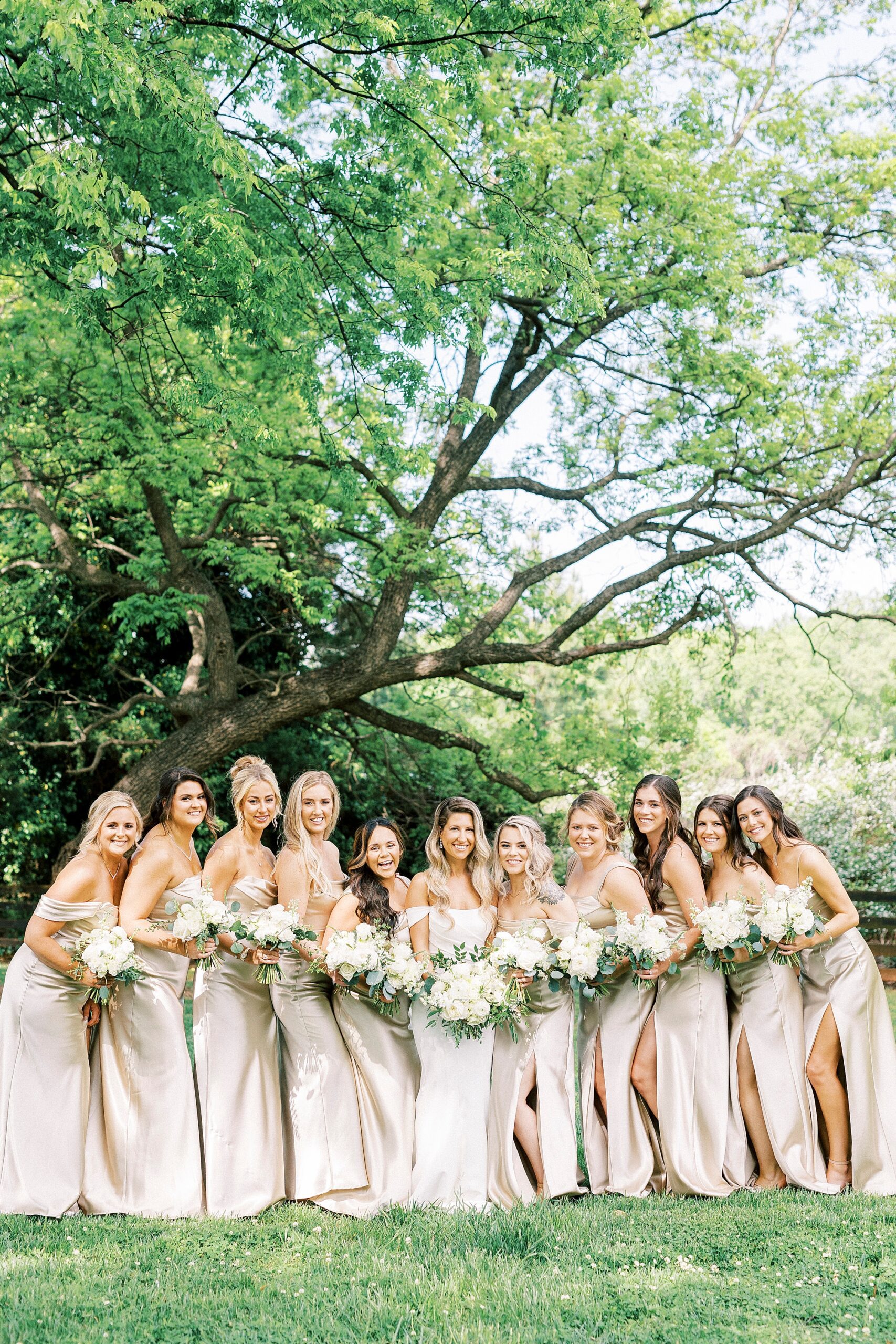 bride poses with bridesmaids in satin pink gowns
