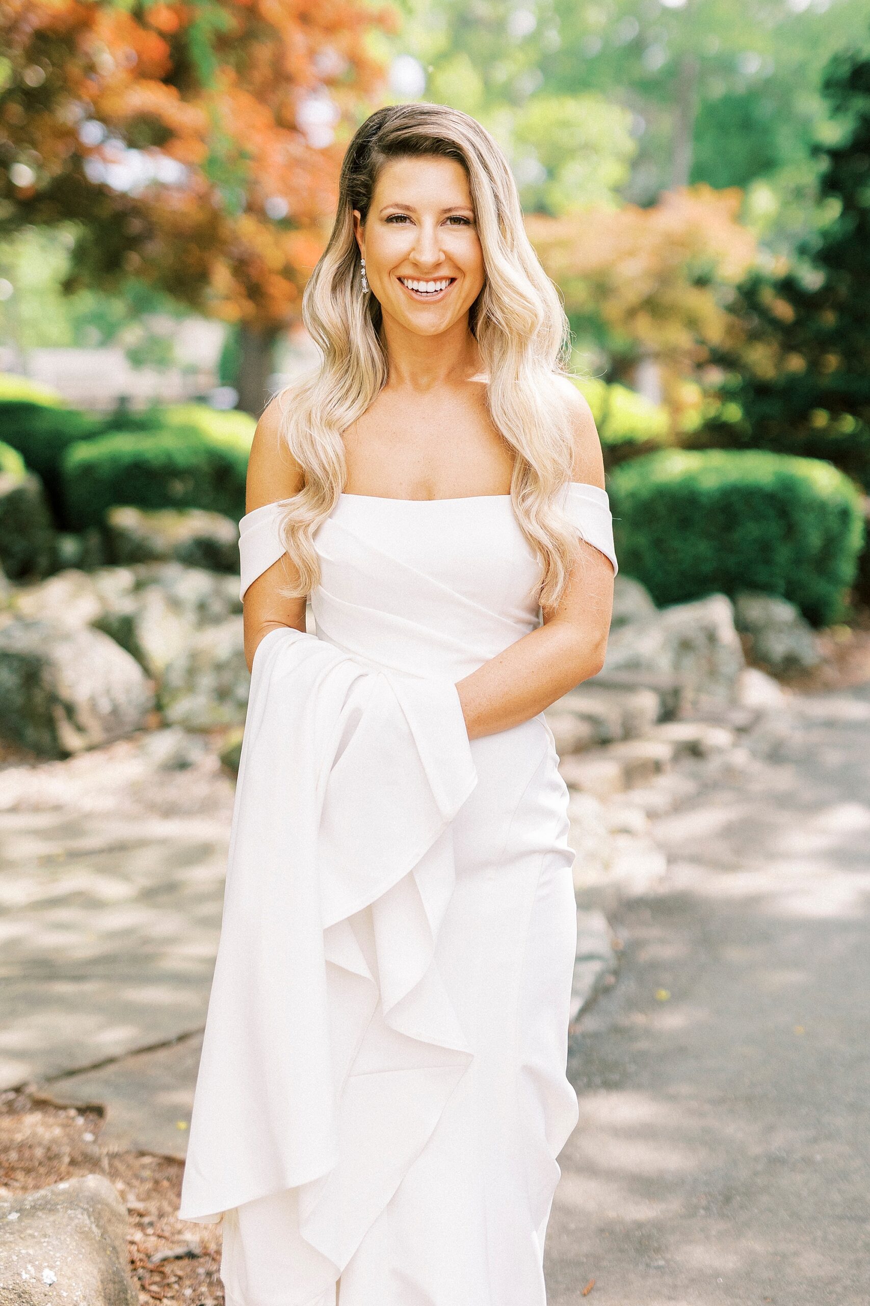 bride holds up skirt of wedding gown walking through the garden
