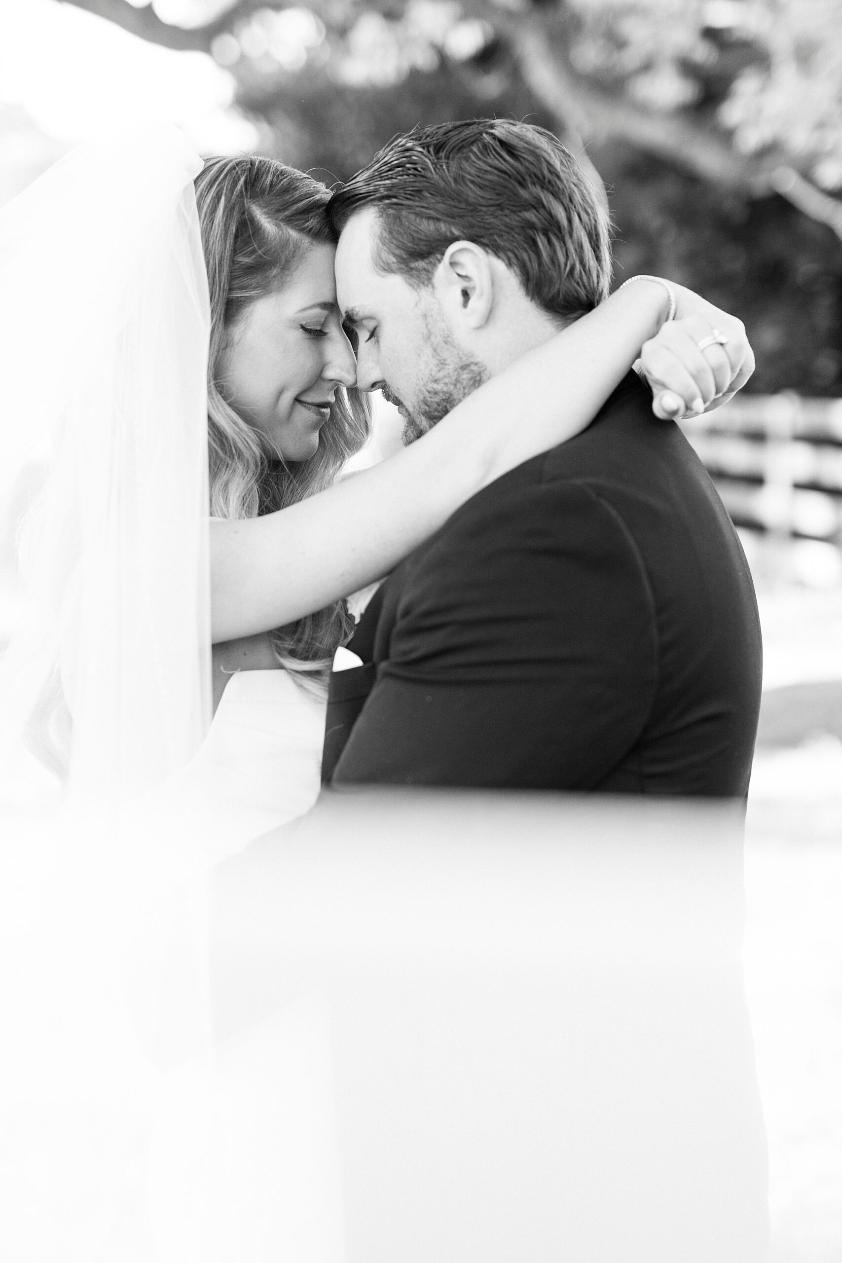 bride hugs groom around neck smiling at him