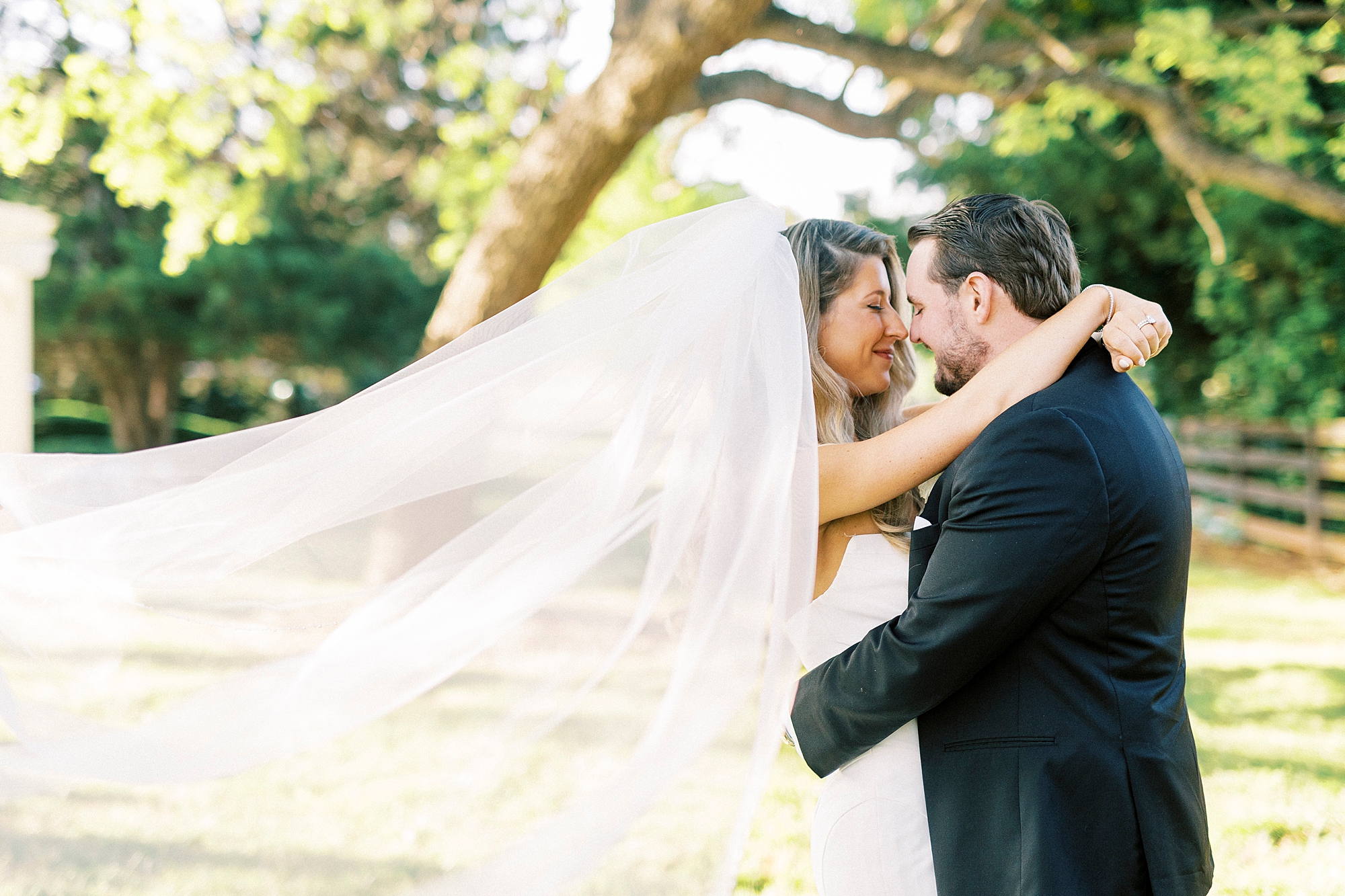 bride and groom lean heads together with her veil floating behind them at the Venues at Langtree