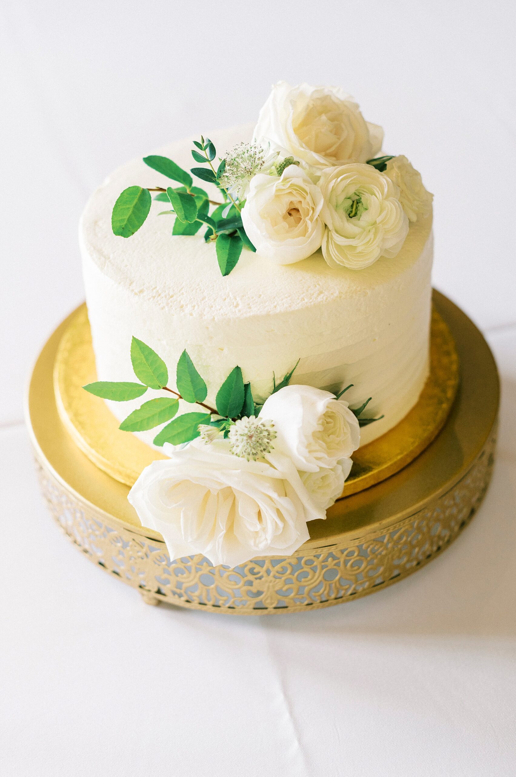 one tiered wedding cake with ivory roses and greenery