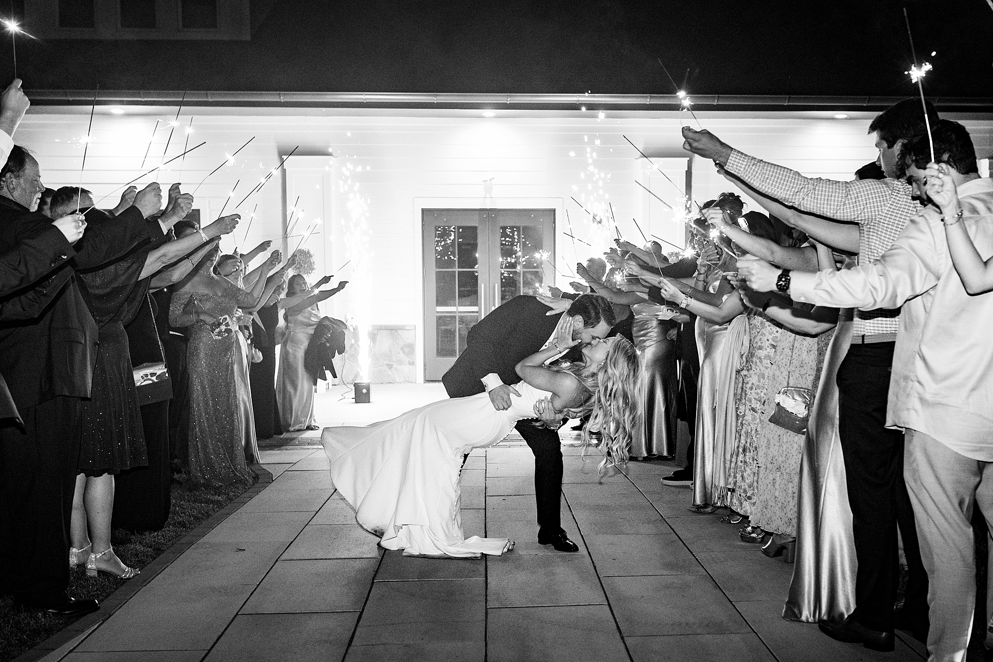 groom dips bride kissing her during sparkler exit at the Venues at Langtree