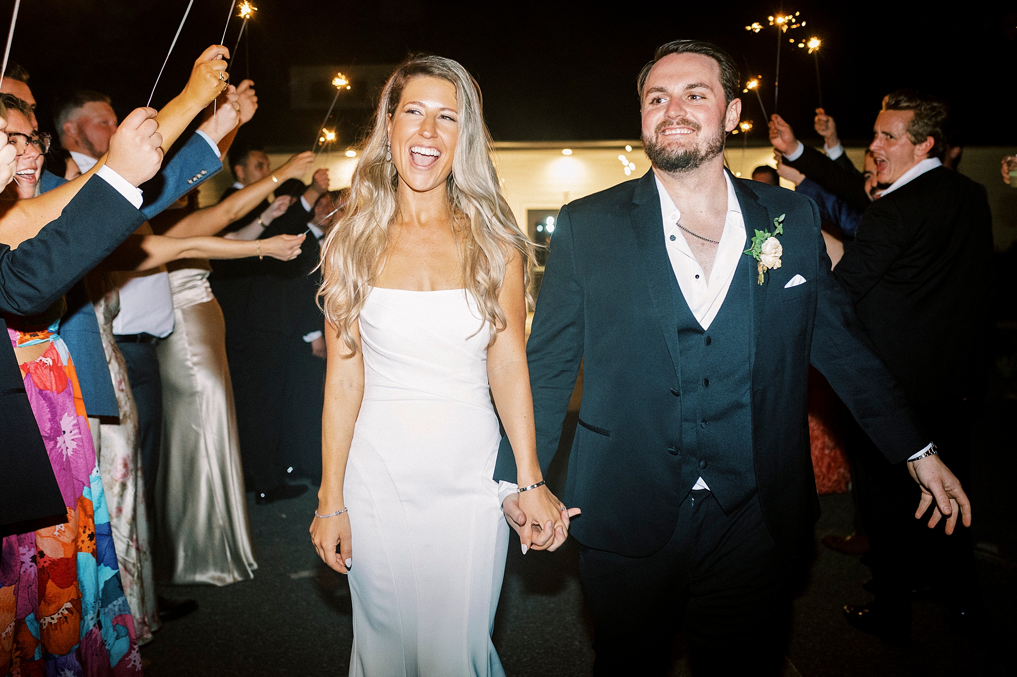 bride and groom hold hands walking through sparkler tunnel