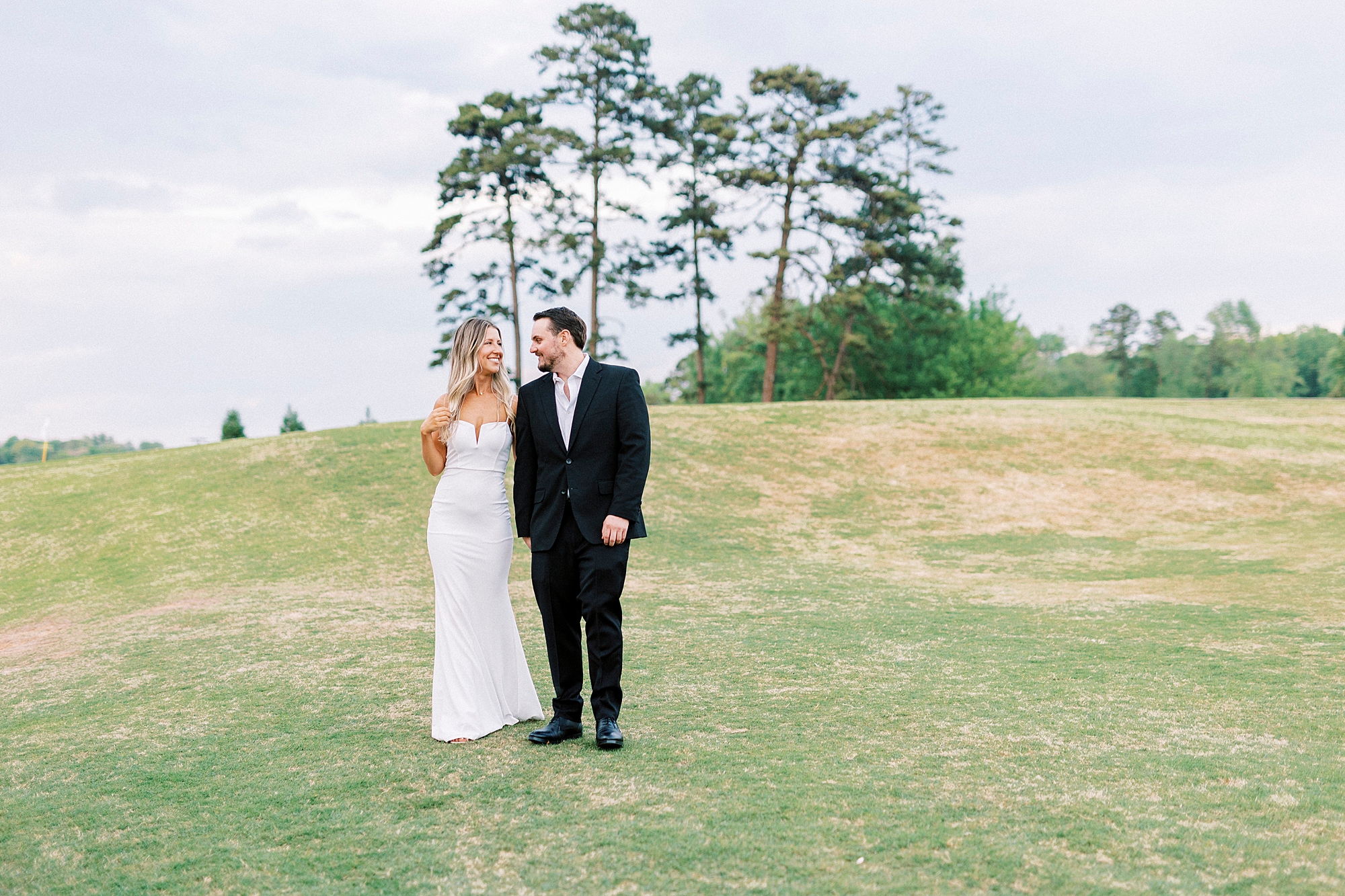 bride and groom hold hands standing on hill outside the Venues at Langtree
