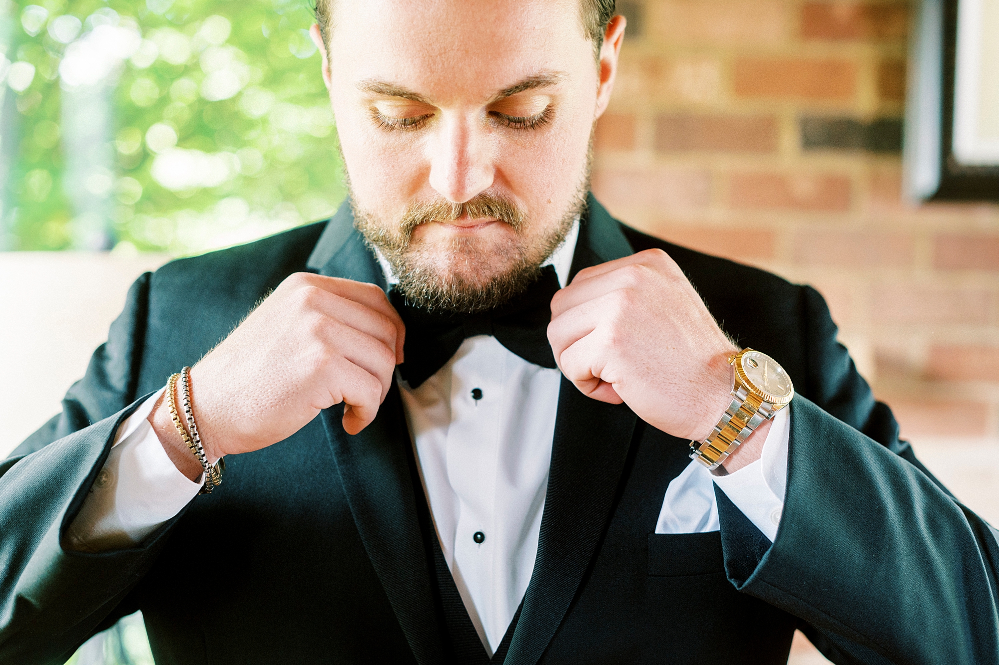 groom adjust black bow tie during prep for North Carolina wedding