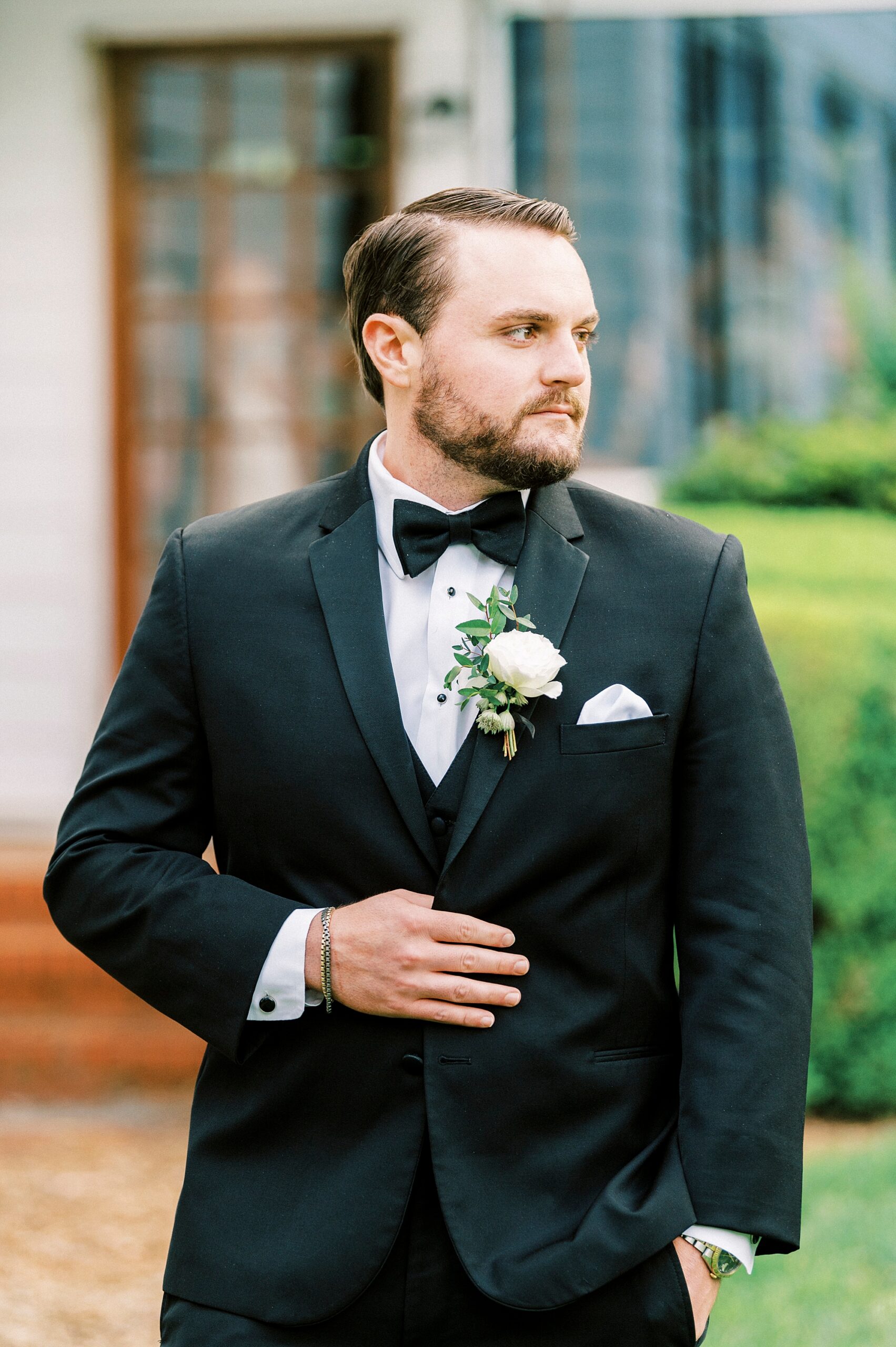 groom holds lapel of black suit before spring wedding