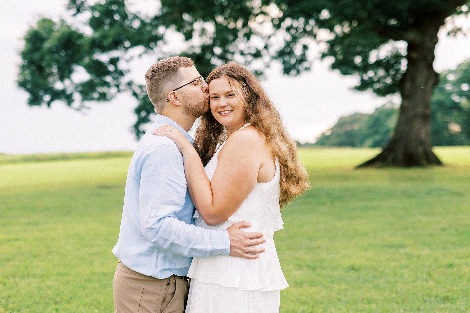 man kisses woman's forehead on lawn at Summerfield Farms