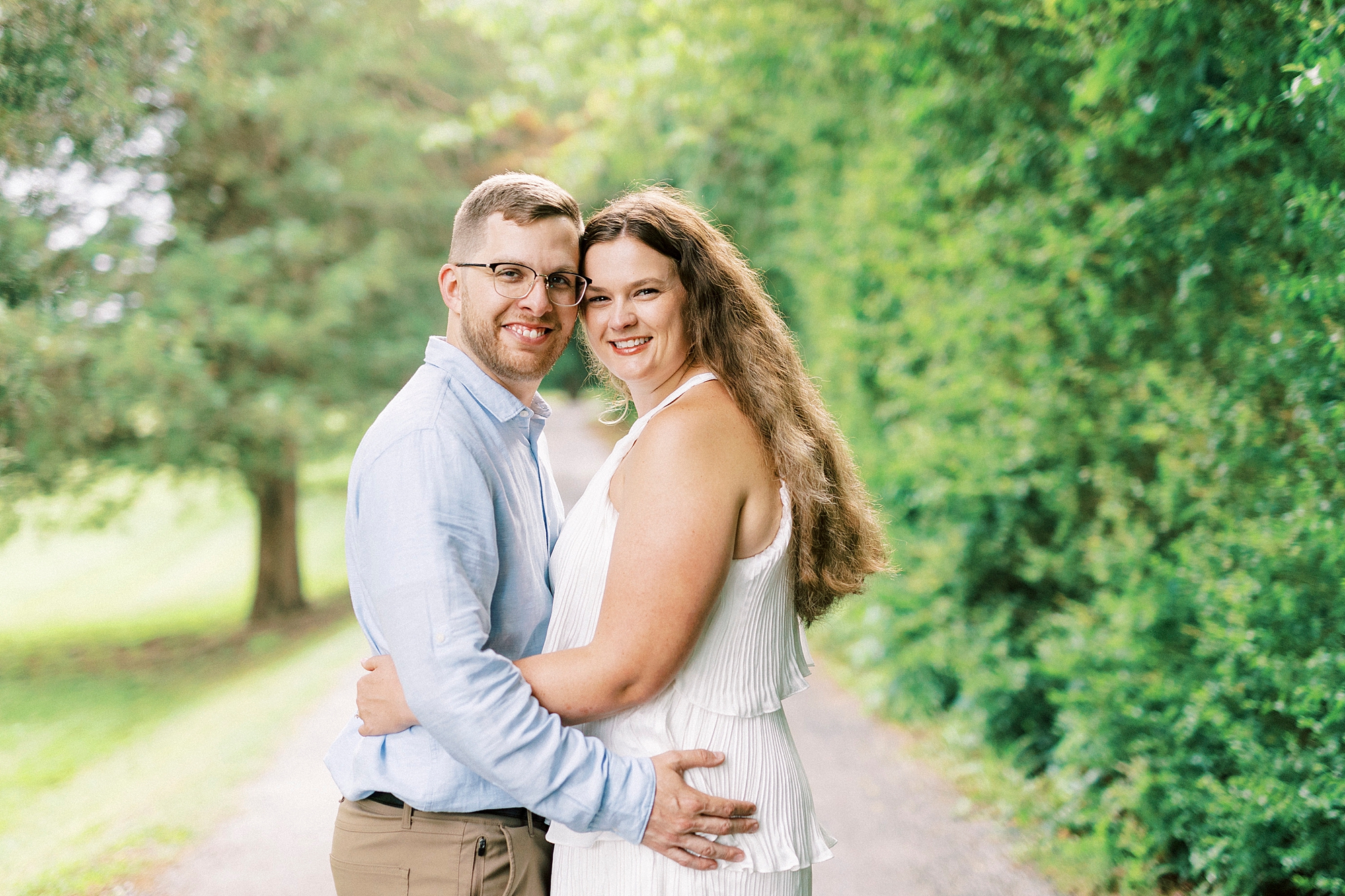 couple hugs on walkway leaning heads together at Summerfield Farms