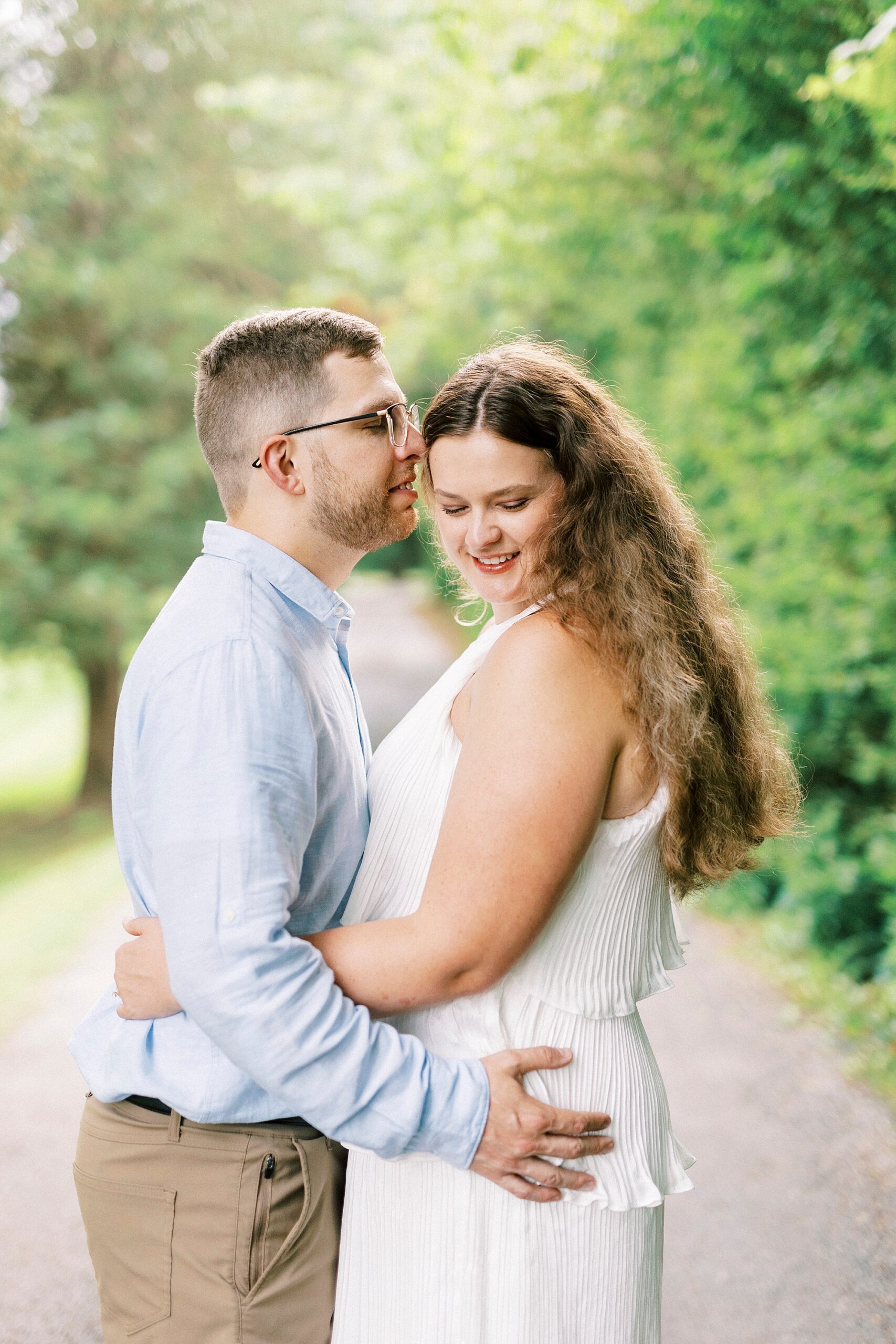 man kisses woman in white dress on driveway at Summerfield Farms