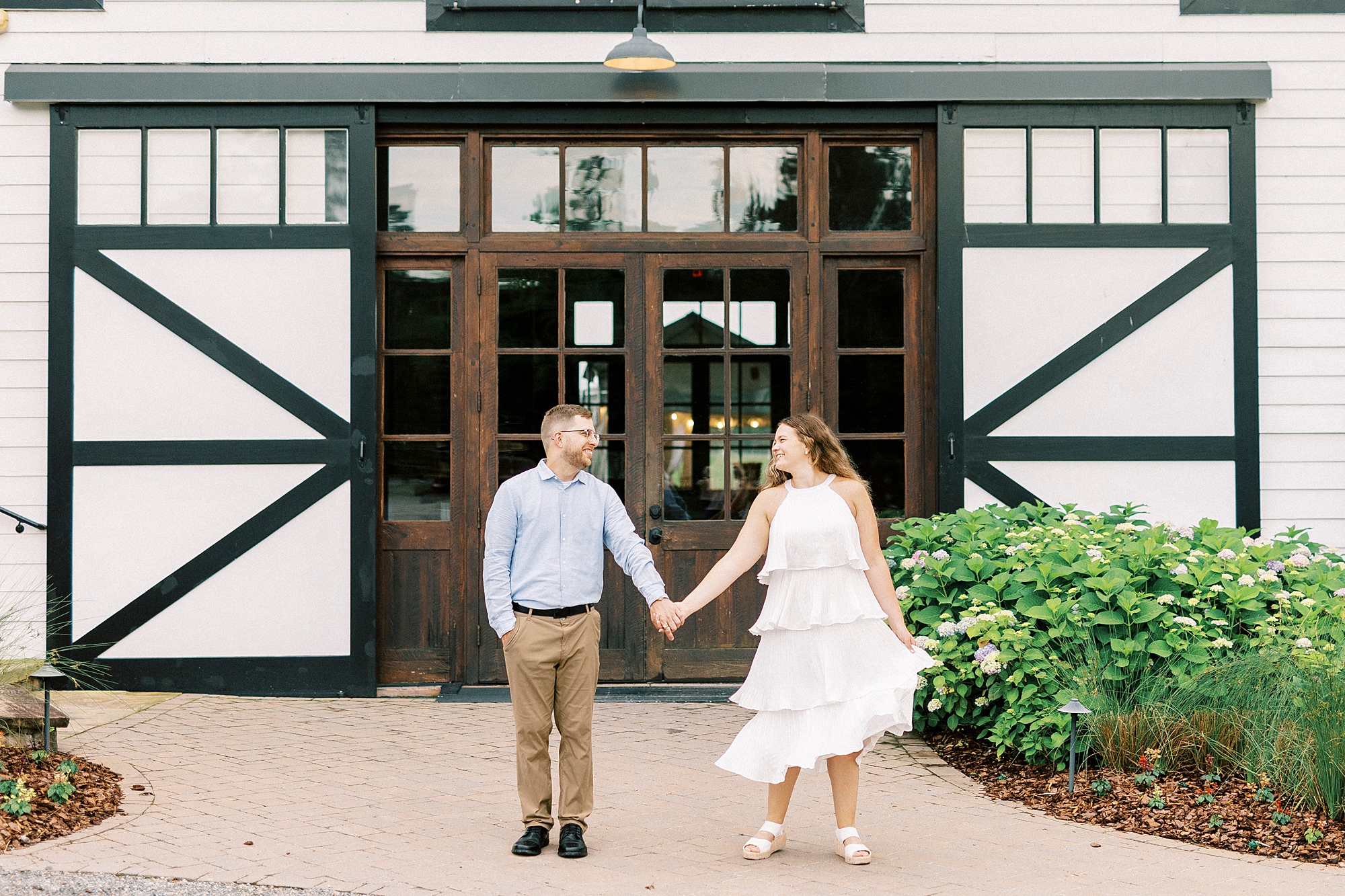 man and woman hold hands in front of barn doors at Summerfield Farms