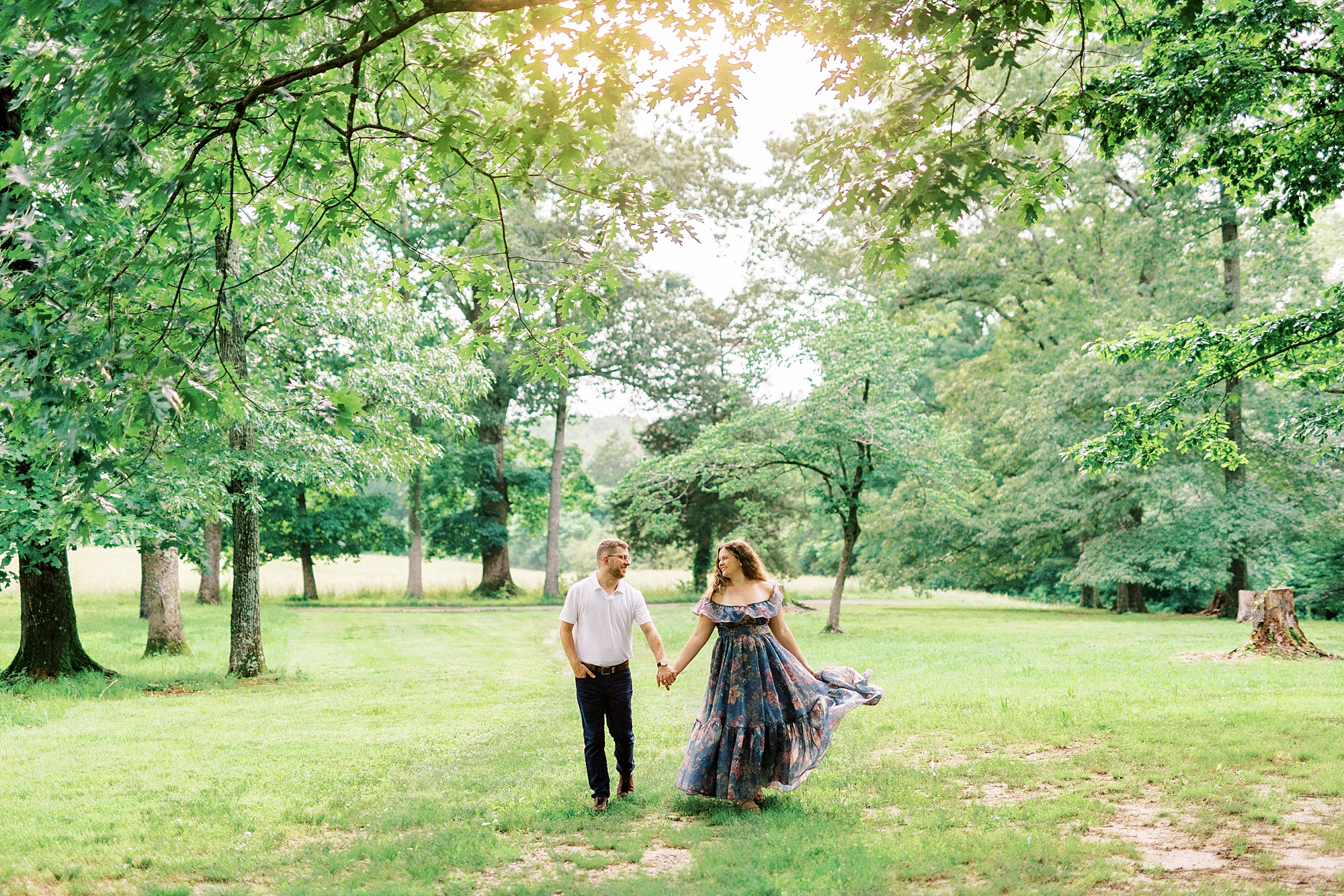 man and woman hold hands walking through field at Summerfield Farms
