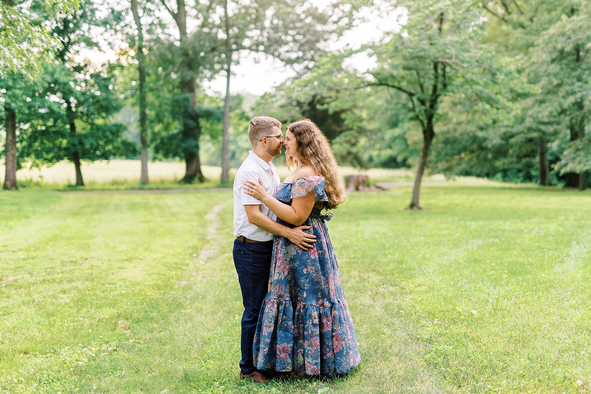 engaged couple hugs together on green lawn at Summerfield Farms