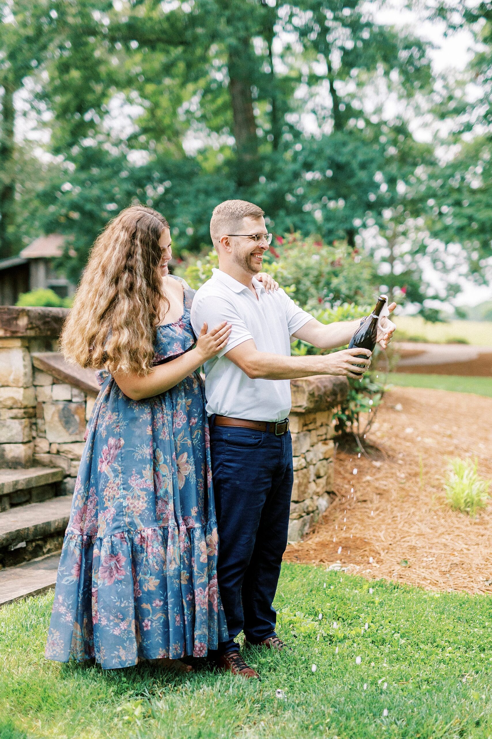 man pops champagne near stone streps at Summerfield Farms