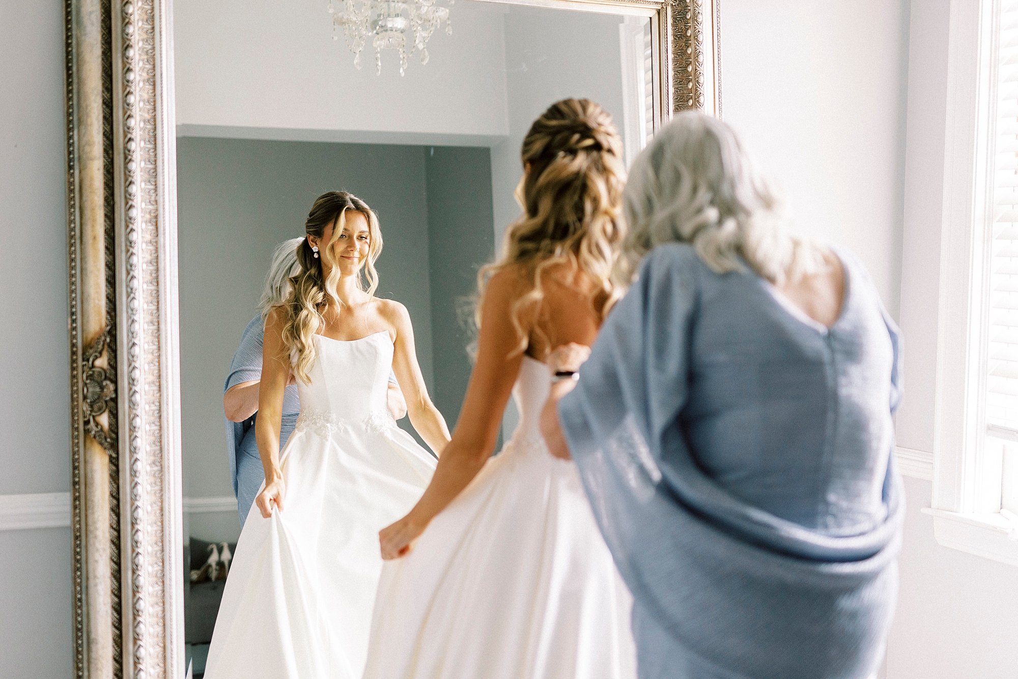 mother helps bride into wedding dress in suite at Separk Mansion