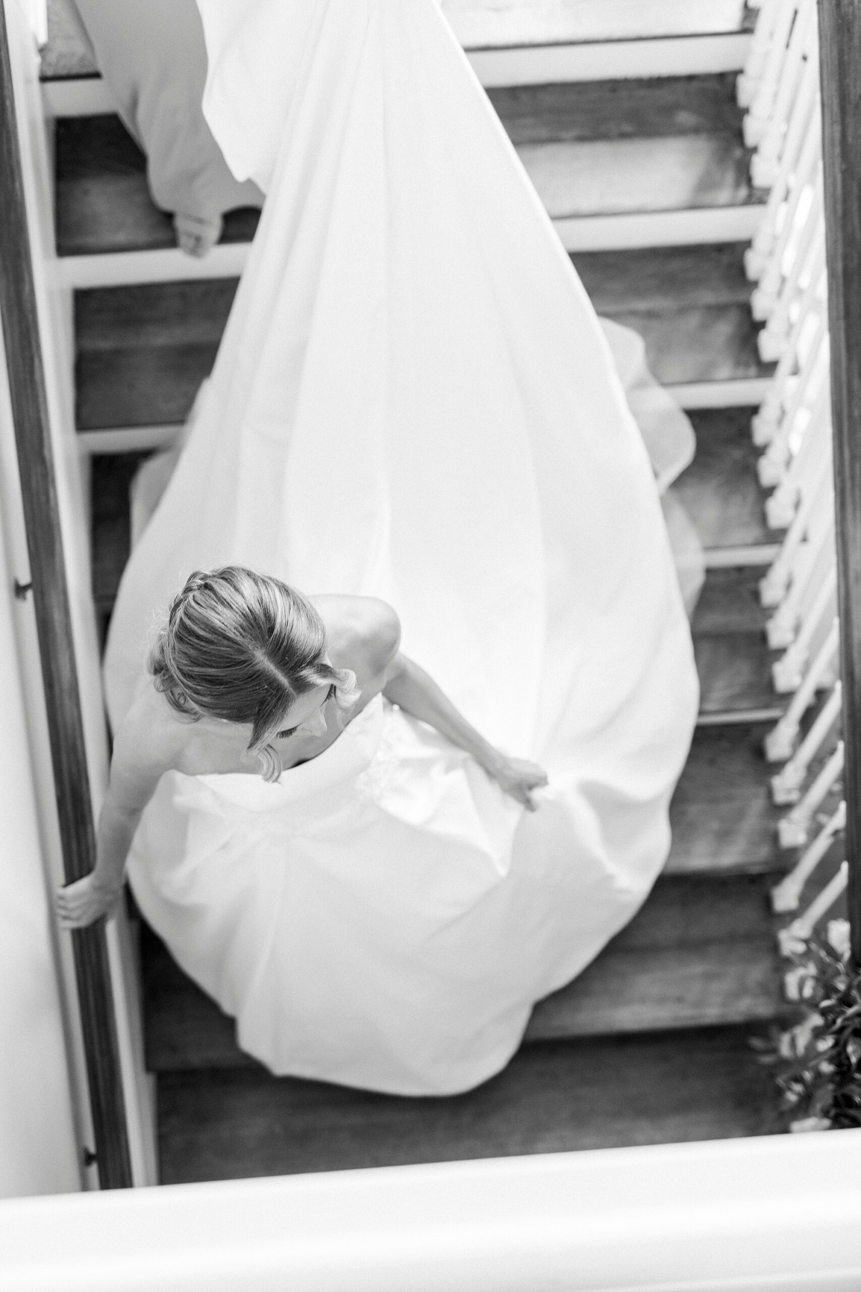 bride walks down staircase inside Separk Mansion with skirt trailing behind her