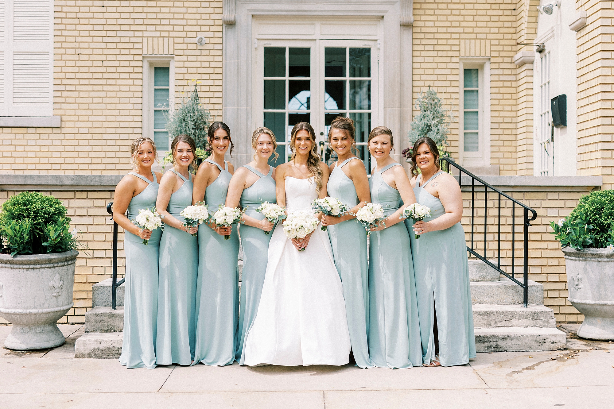 bride stands with bridesmaids in robin's egg blue gowns