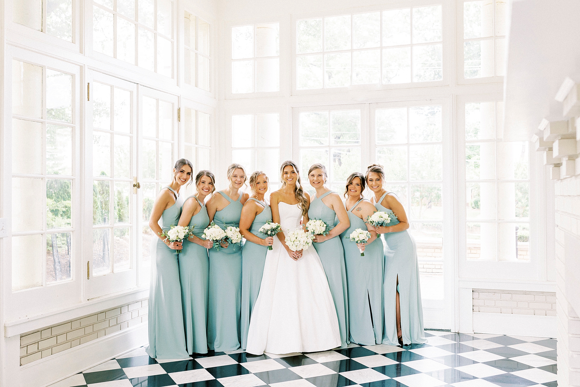 bride and bridesmaids hug together in sunroom at Separk Mansion