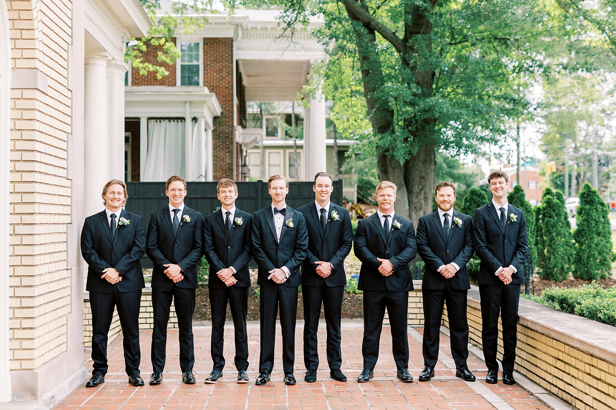 groom stands with groomsmen in line on brick patio at Separk Mansion