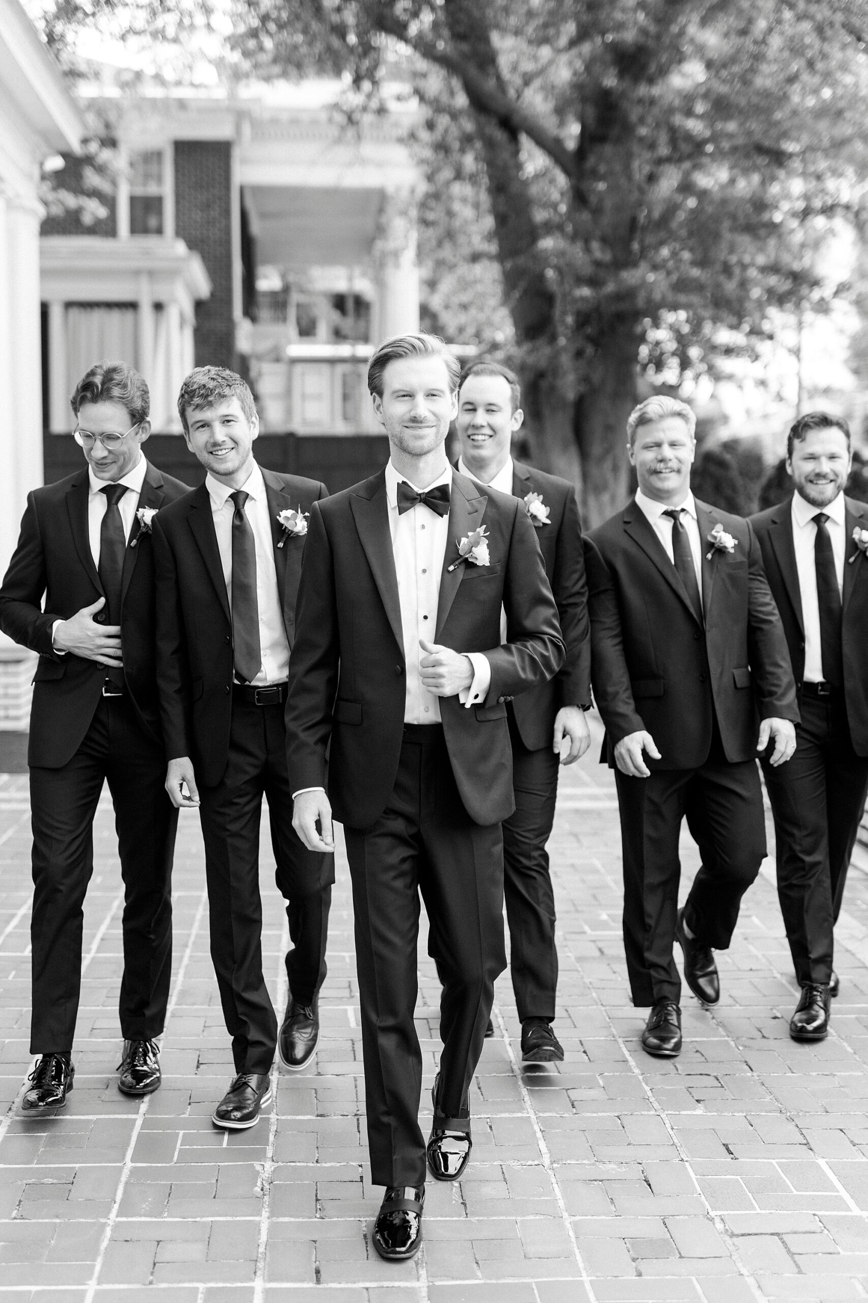 groom and groomsmen walk in black suits for NC wedding 