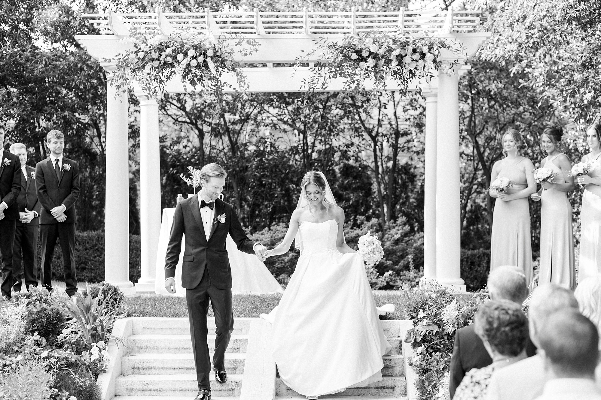 groom escorts bride down steps of arbor at Separk Mansion