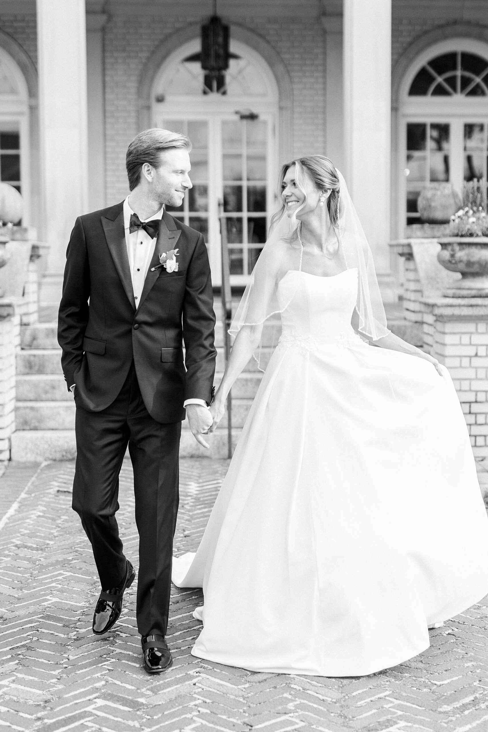 newlyweds hold hands walking on lawn at Separk Mansion