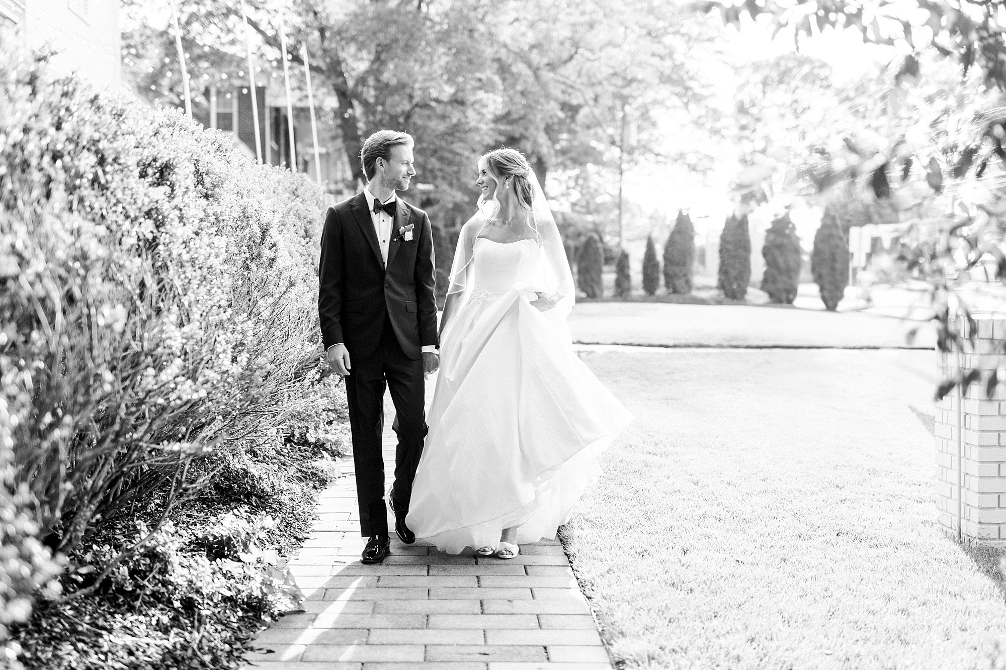 newlyweds hold hands walking along brick pathway in Separk Mansion