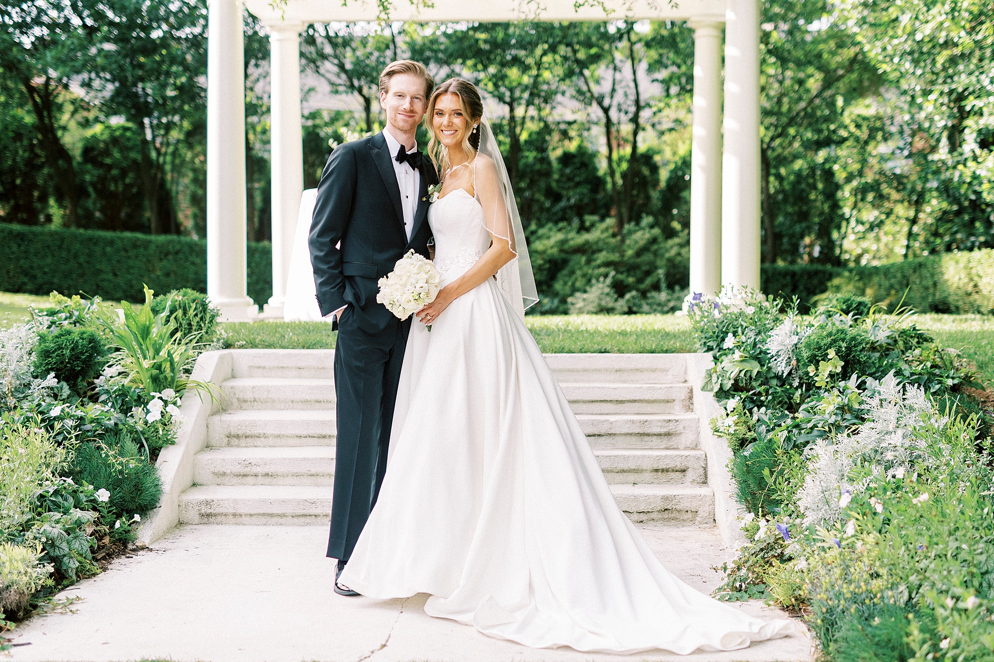 newlyweds hug under stone arbor in garden at Separk Mansion