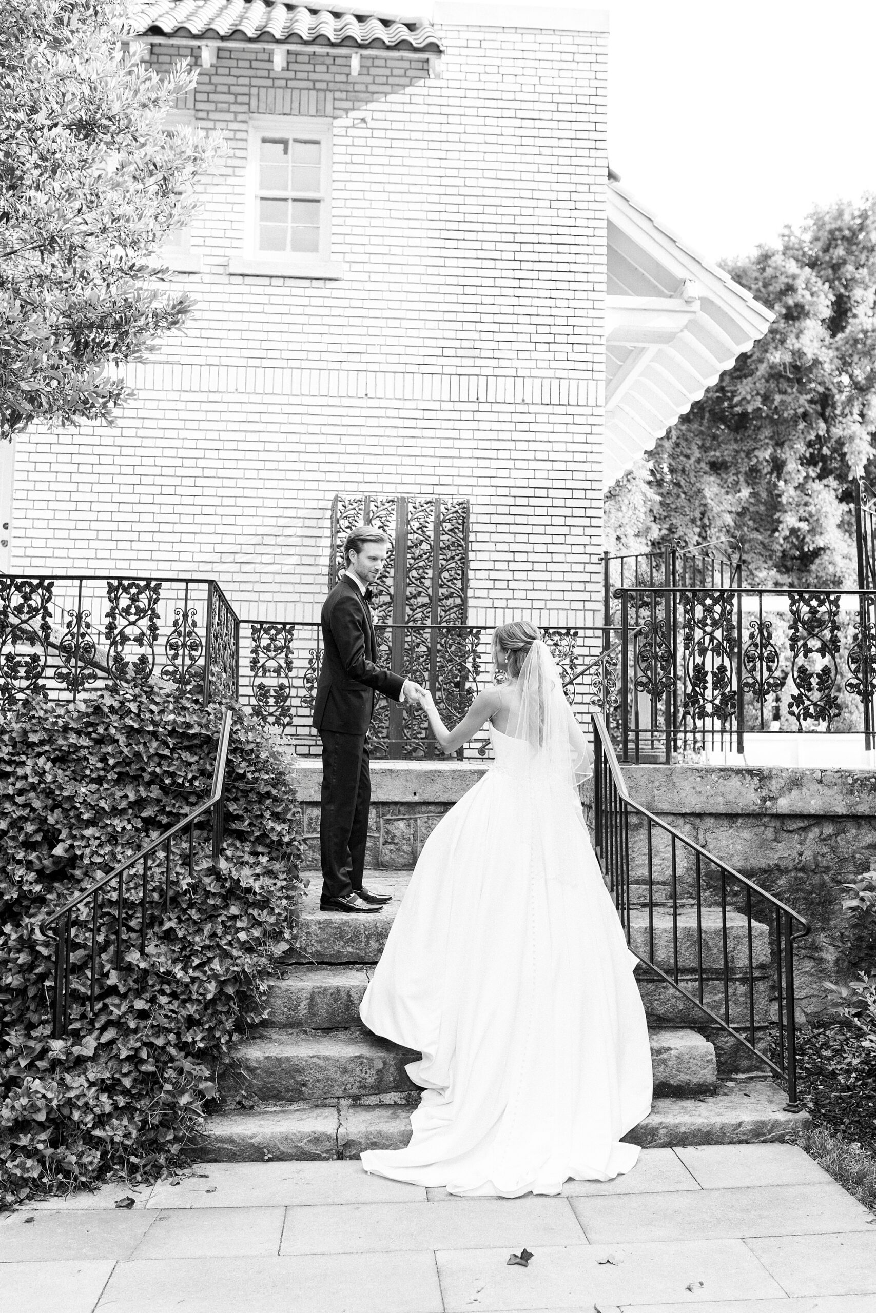 groom helps bride up stone staircase outside Separk Mansion