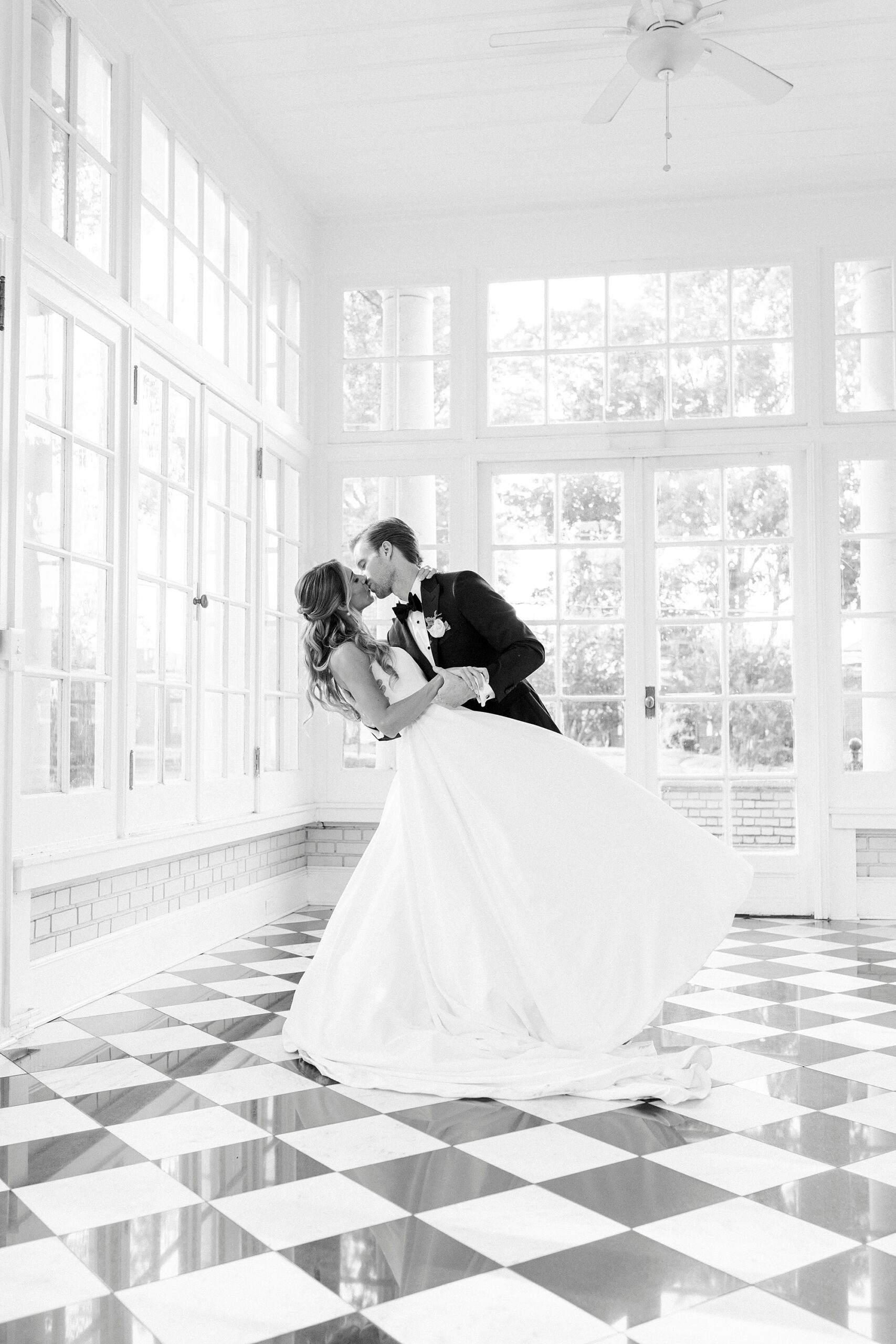 groom kisses bride dipping her in sunroom of Separk Mansion