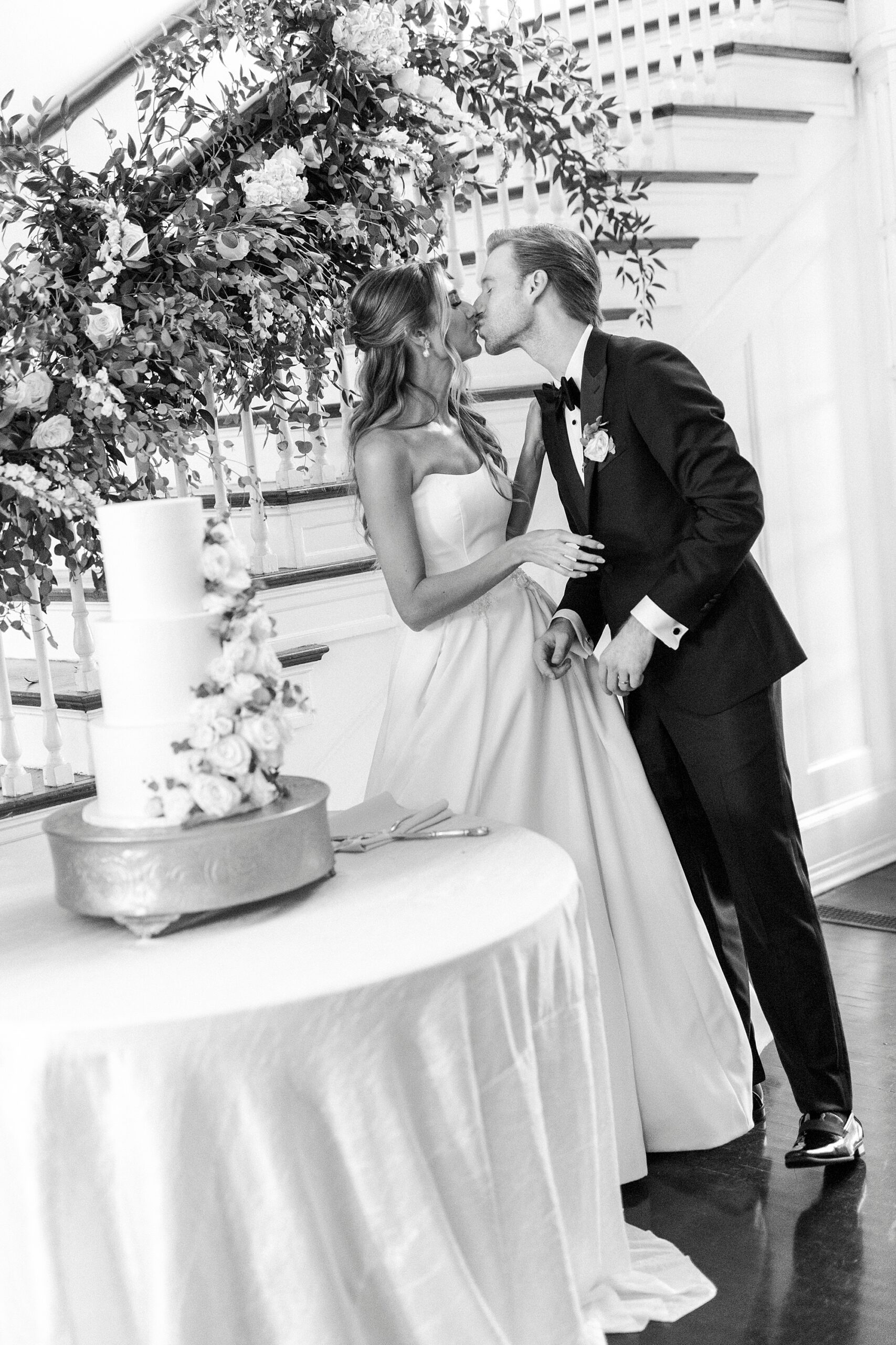 bride and groom kiss by cake table at reception