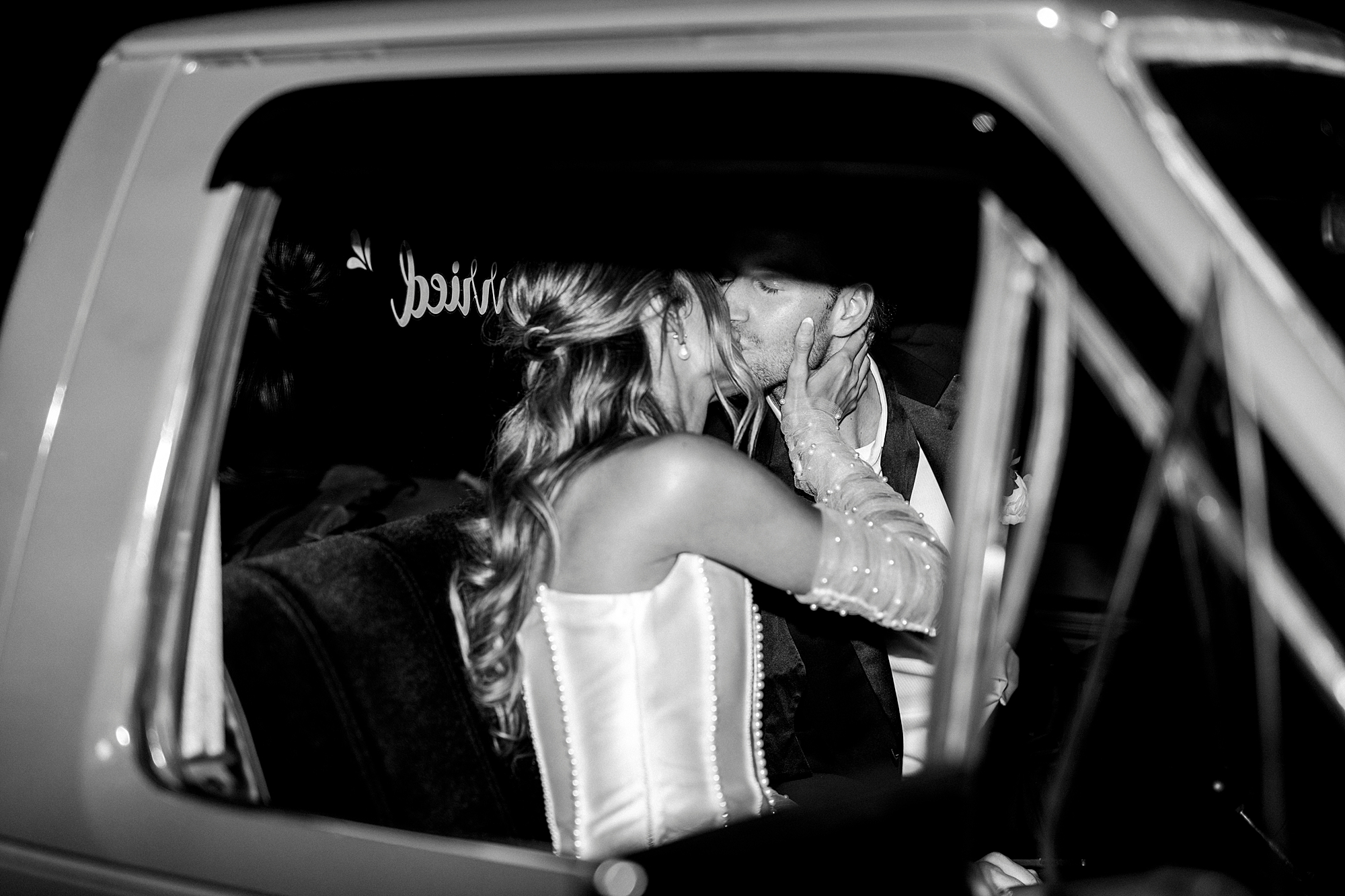 bride and groom kiss inside classic car