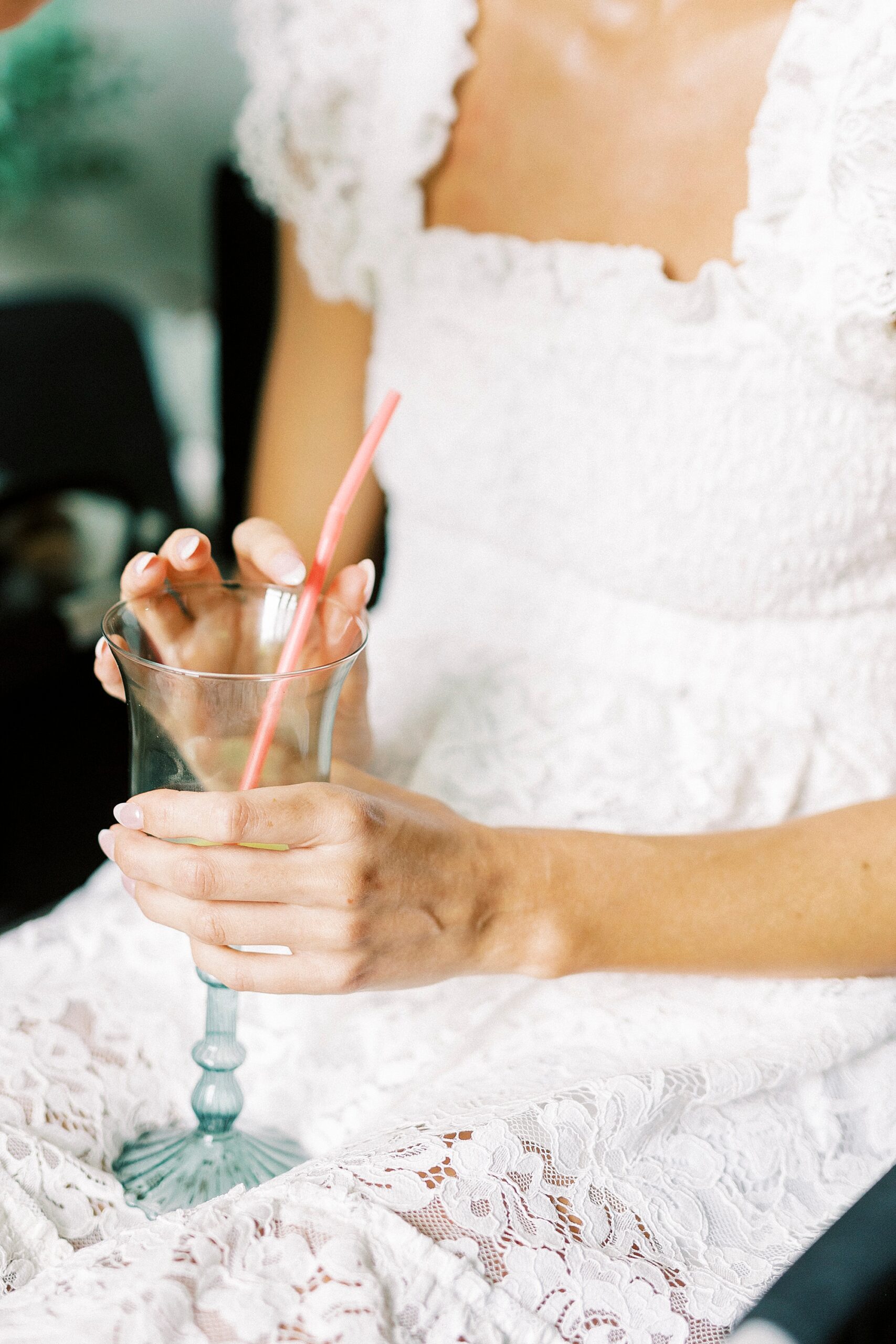 bride holds glass with custom straw on lap