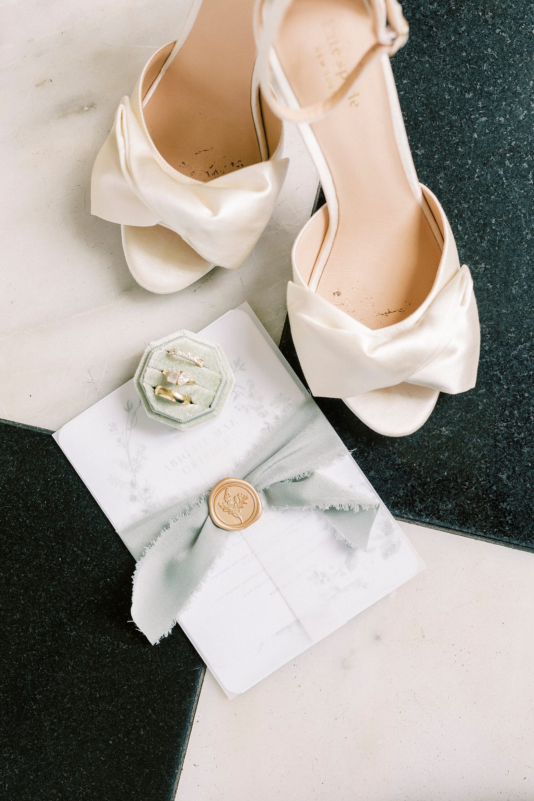 bride's white shoes sit next to invitation suite for spring wedding