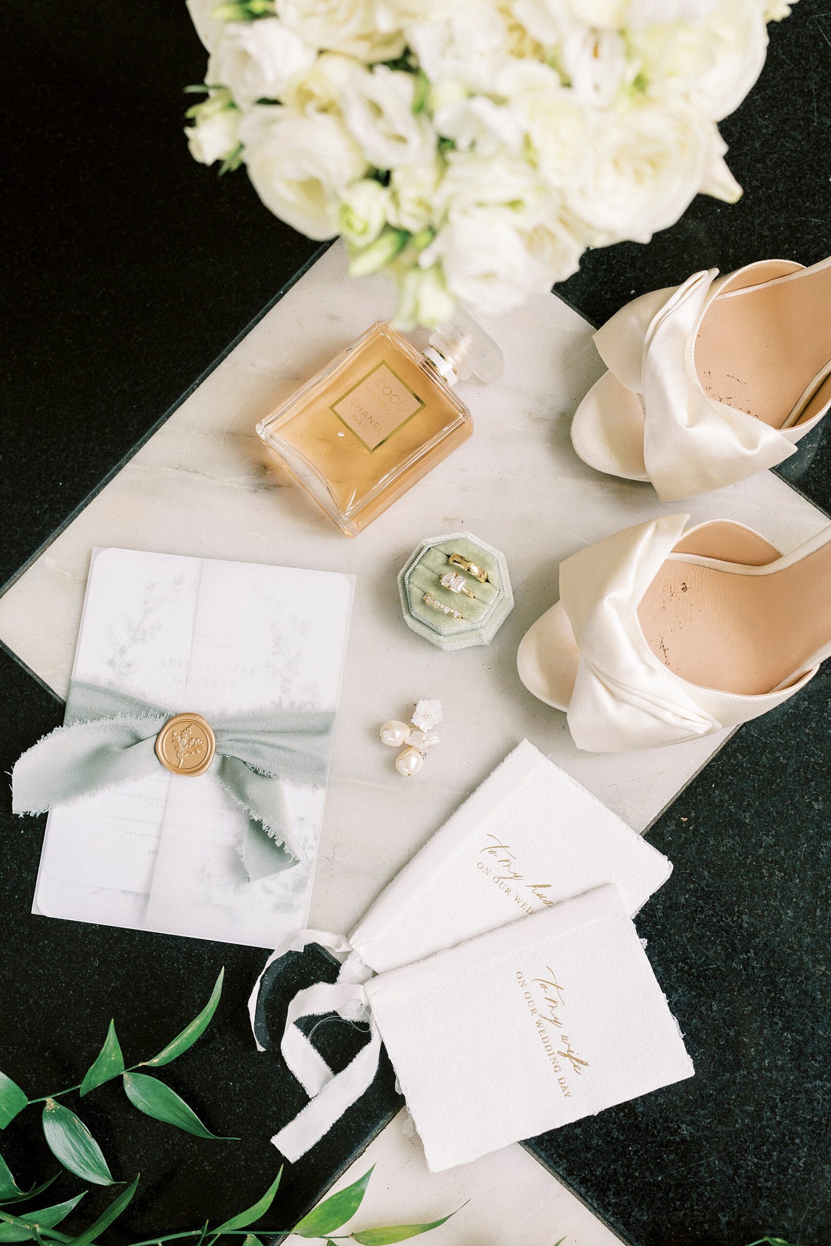bride's white shoes, spring wedding invitation, and white flowers 