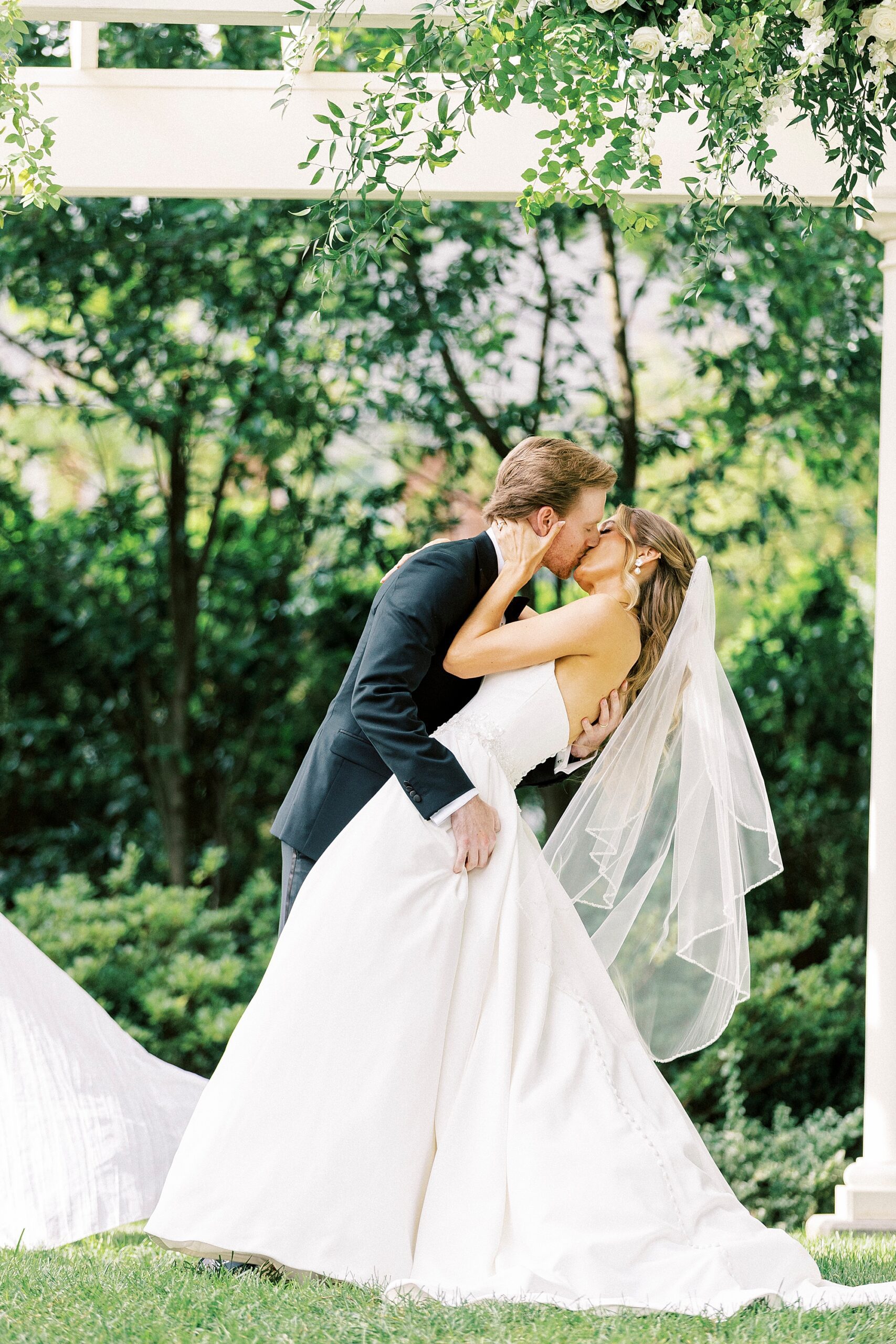 groom kisses bride dipping her slightly during wedding ceremony in garden of Separk Mansion