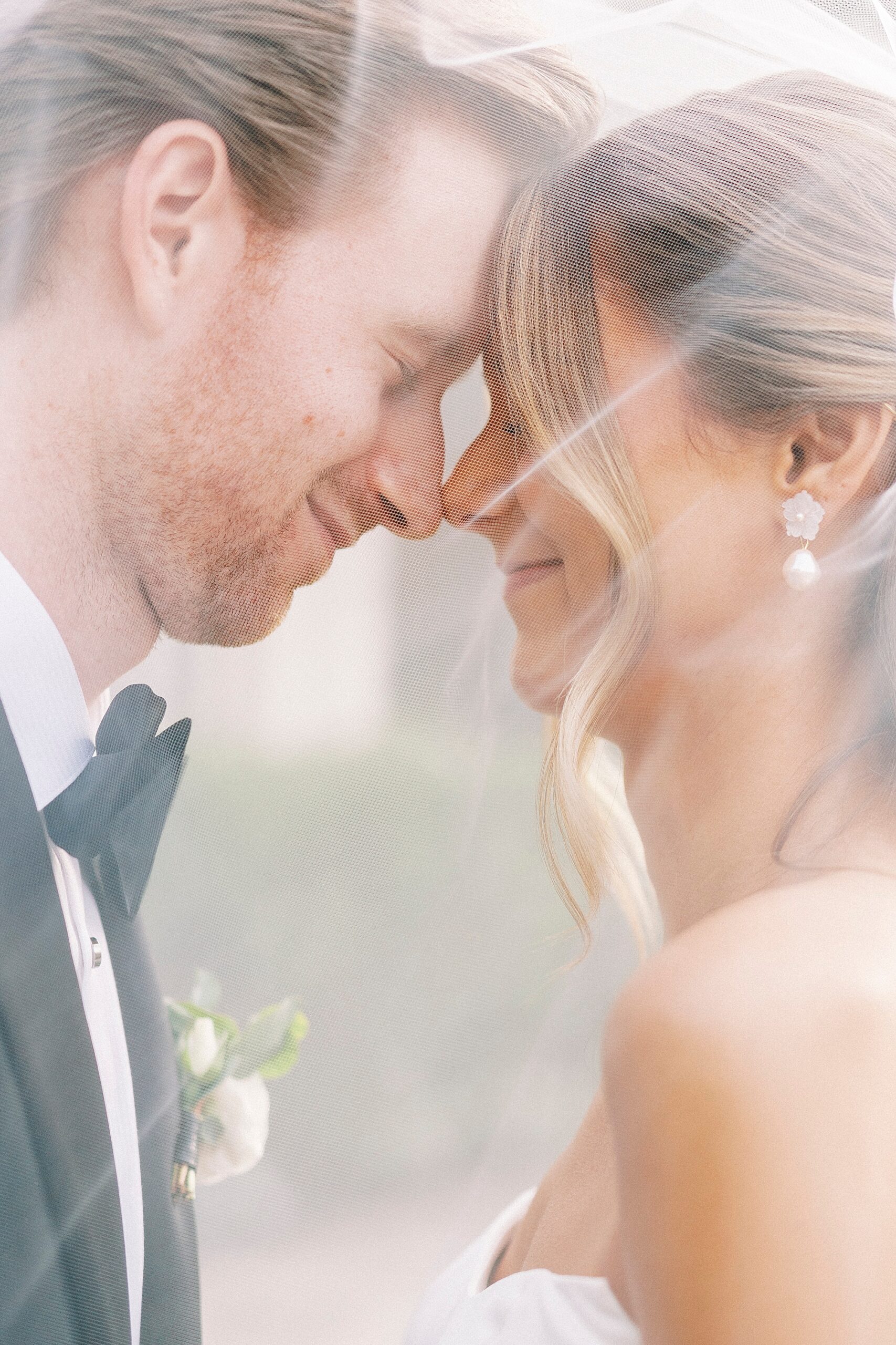 bride and groom grin together under bride's veil